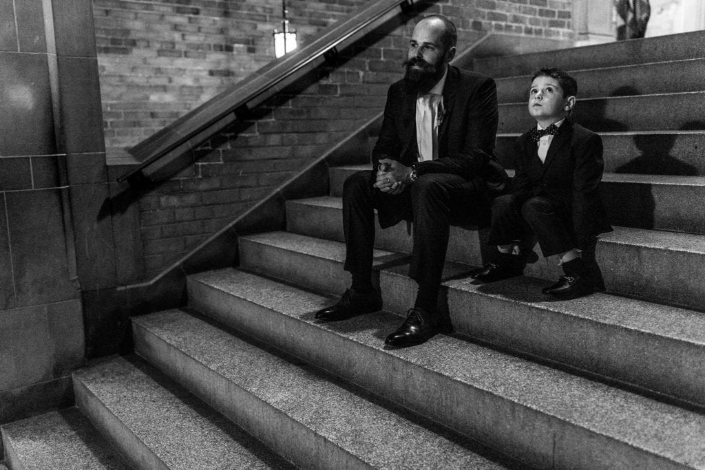 boy shoves hands in socks while sitting on steps with groom