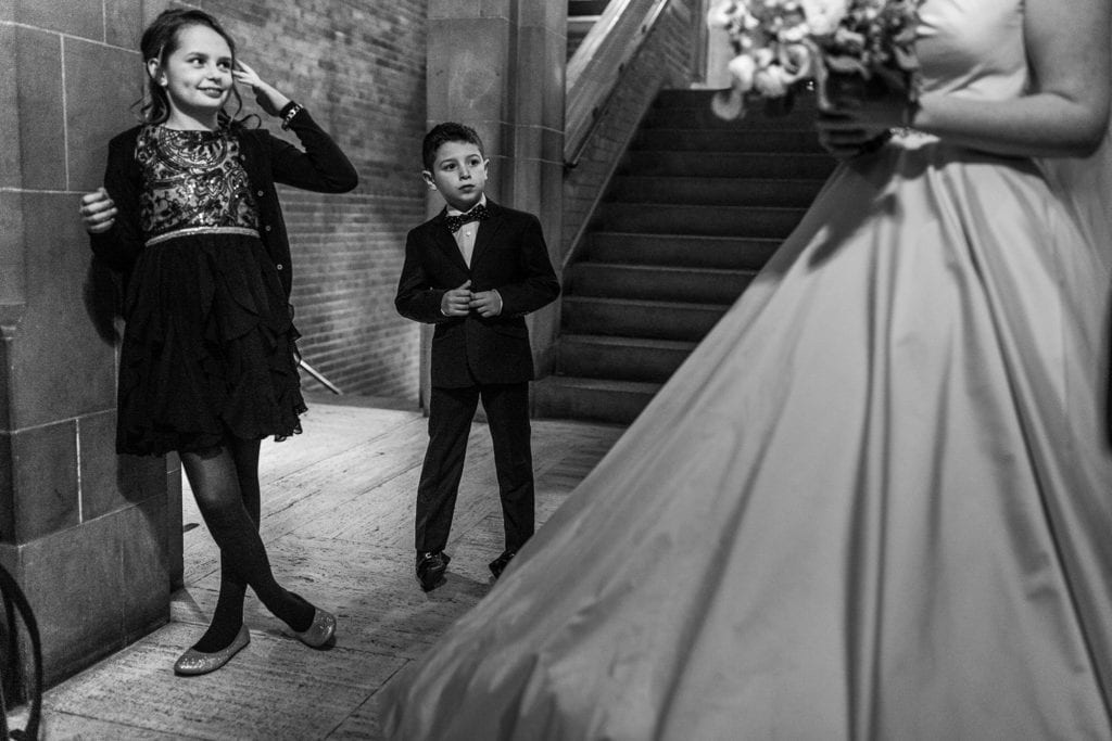 girl and young boy look up at bride in Hart House hallway