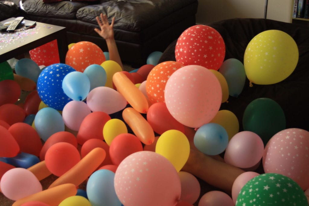 arm reaching out from under a pile of balloons