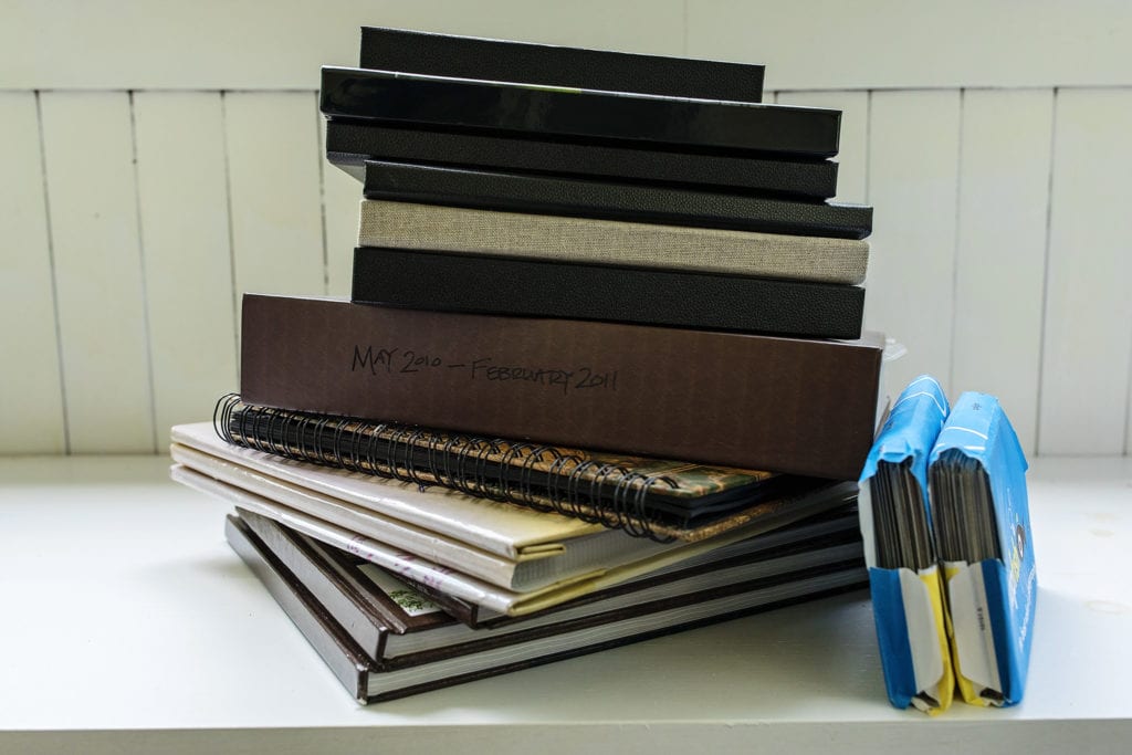 stack of photo albums with two blue envelopes of prints