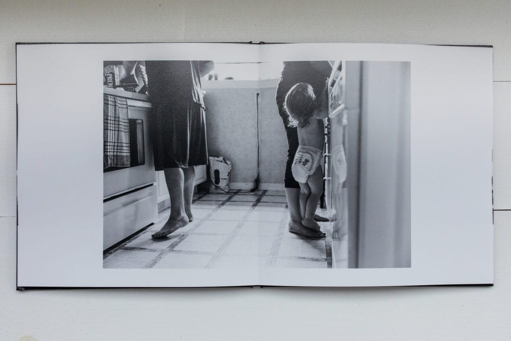 documentary family photography album pages featuring little girl standing on mom's foot in kitchen while trying to get a better view of countertop