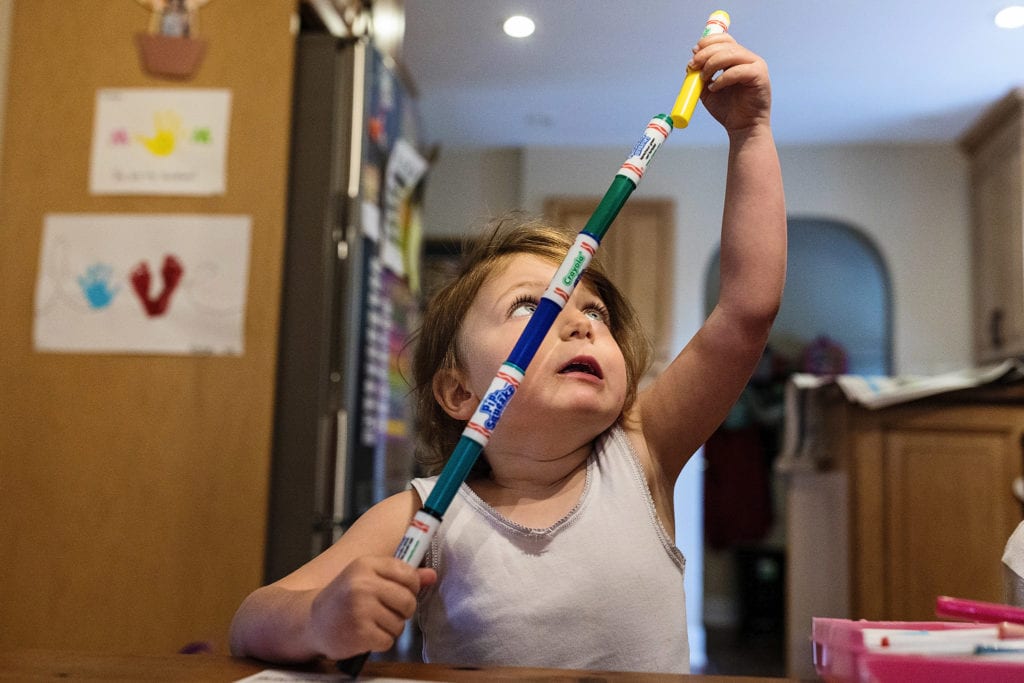 little girl in white tank top stretches to make marker tower