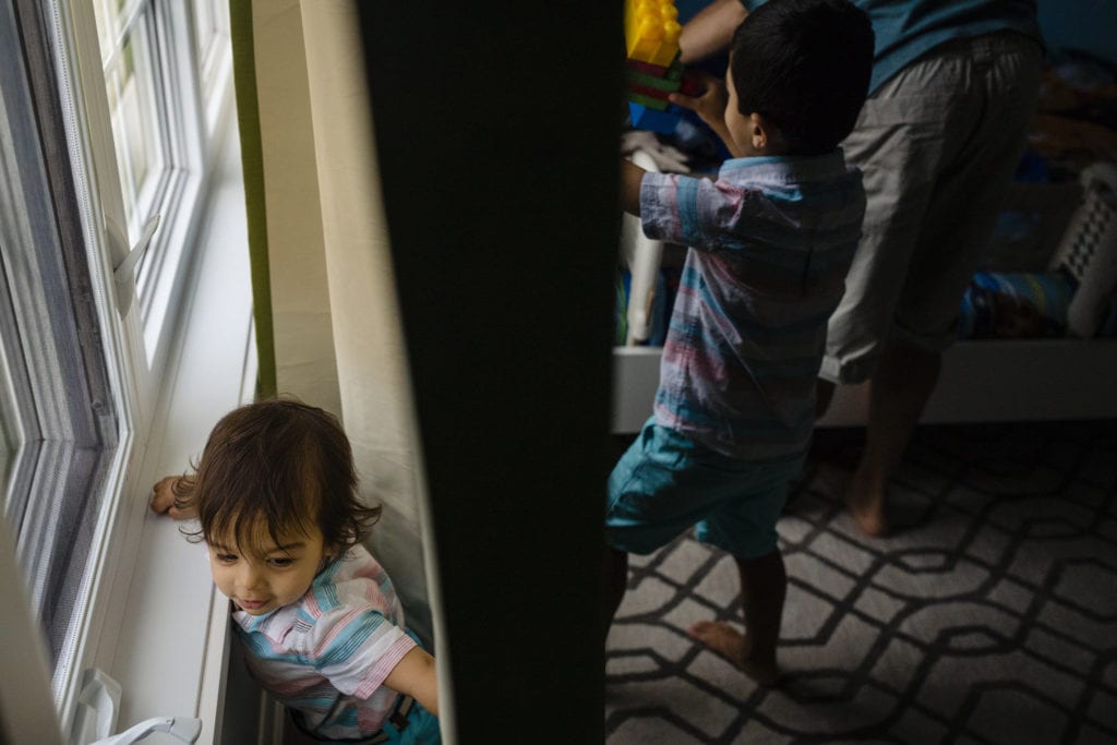 boys play on either side of window curtain