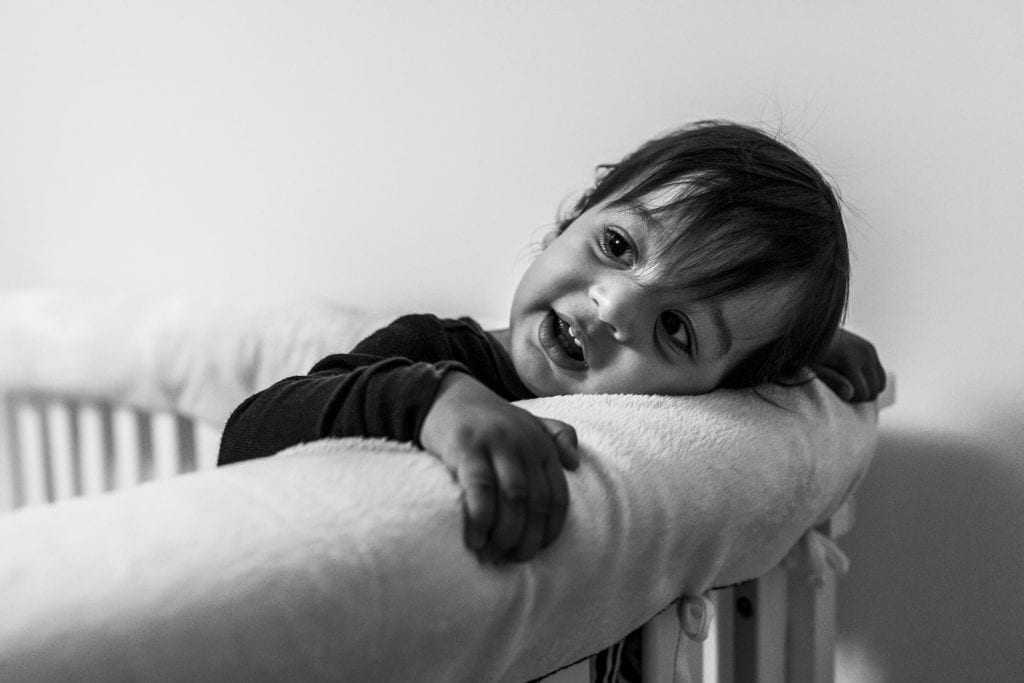 toddler rests head on crib railing