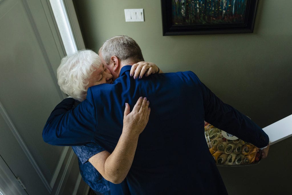 groom hugs crying mother at front door