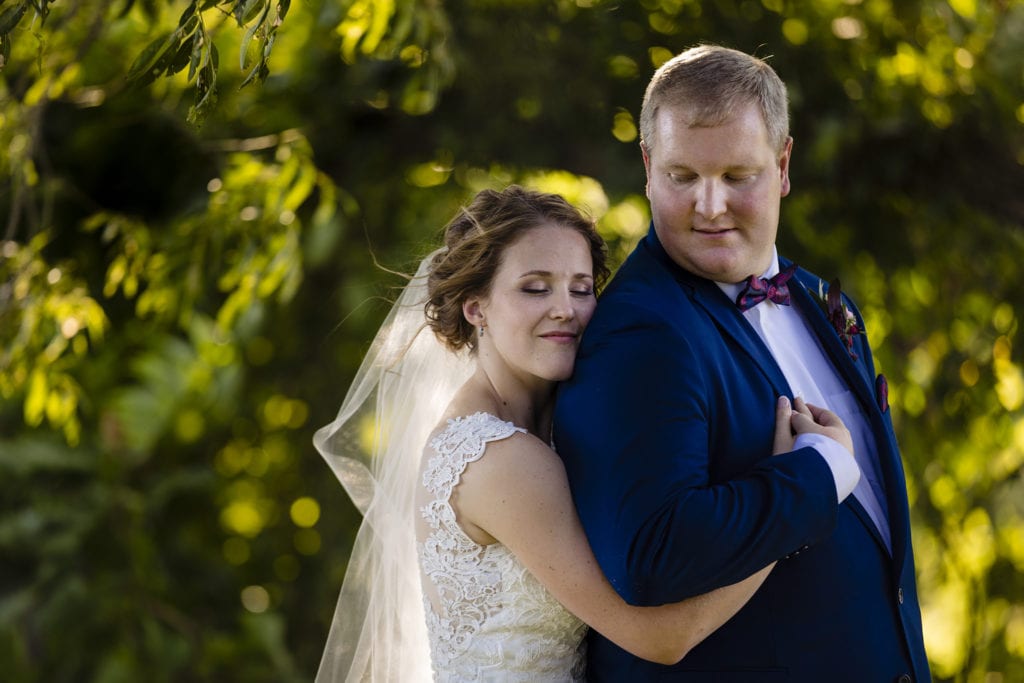 bride in lace gown hugs groom in royal blue suit