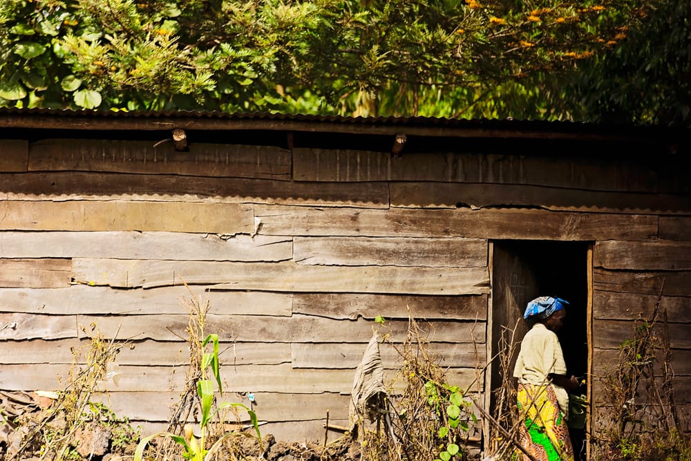 woman walking past doorway of wooden shack