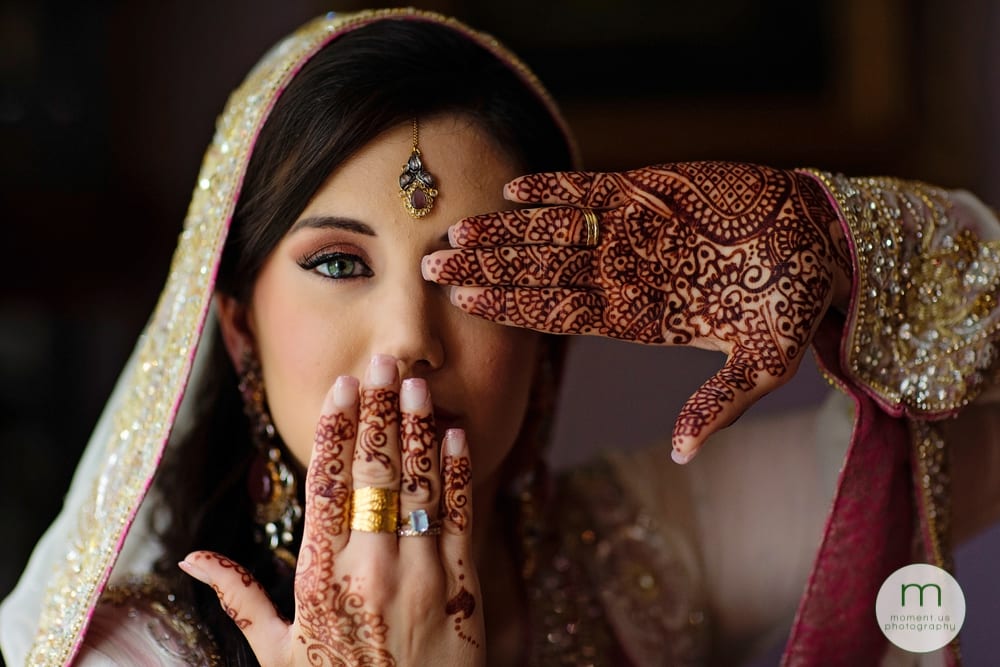 bride with mehndi hands by face