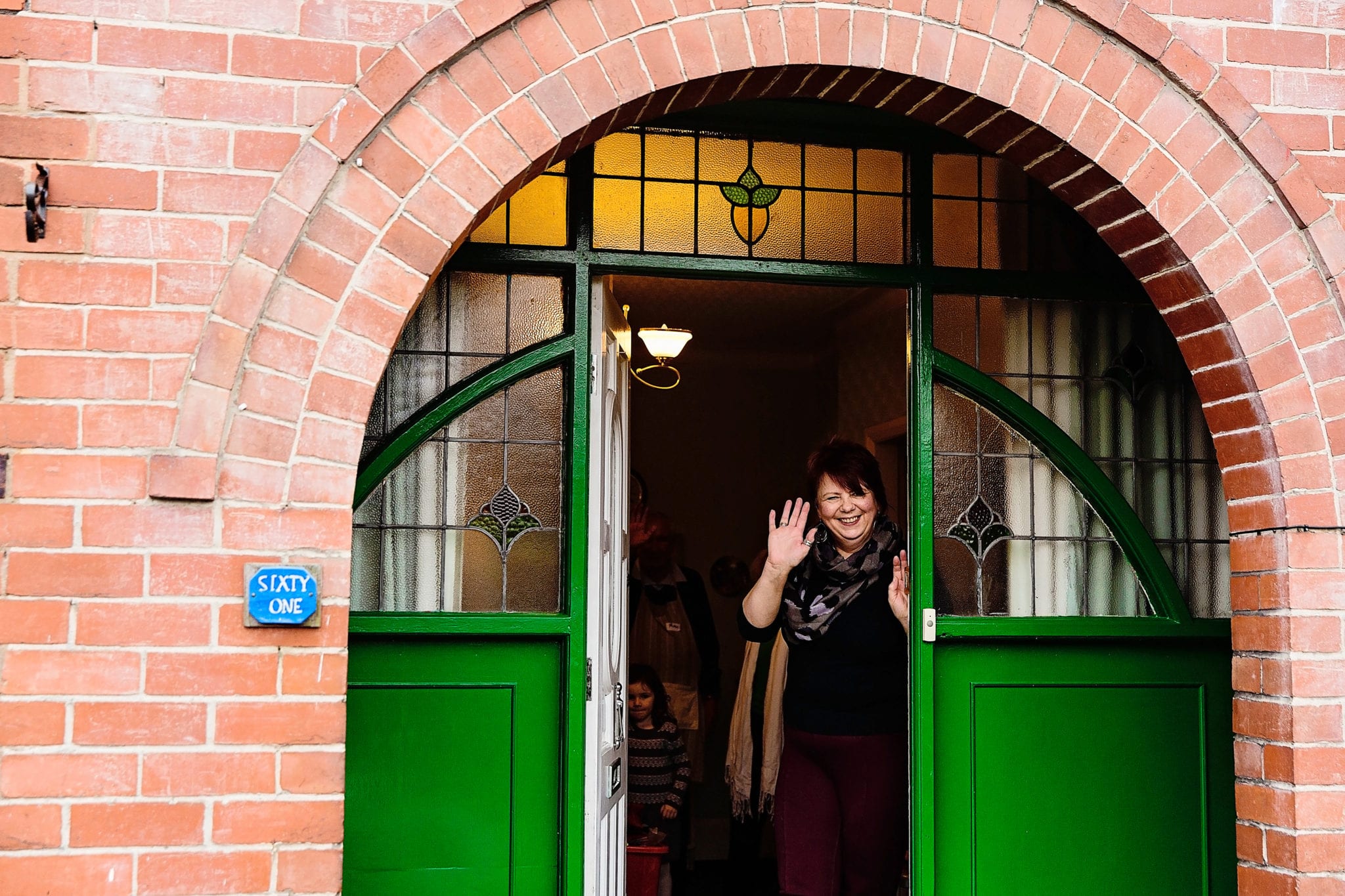 Mom waving goodbye from doorway to guests leaving Manchester family lunch