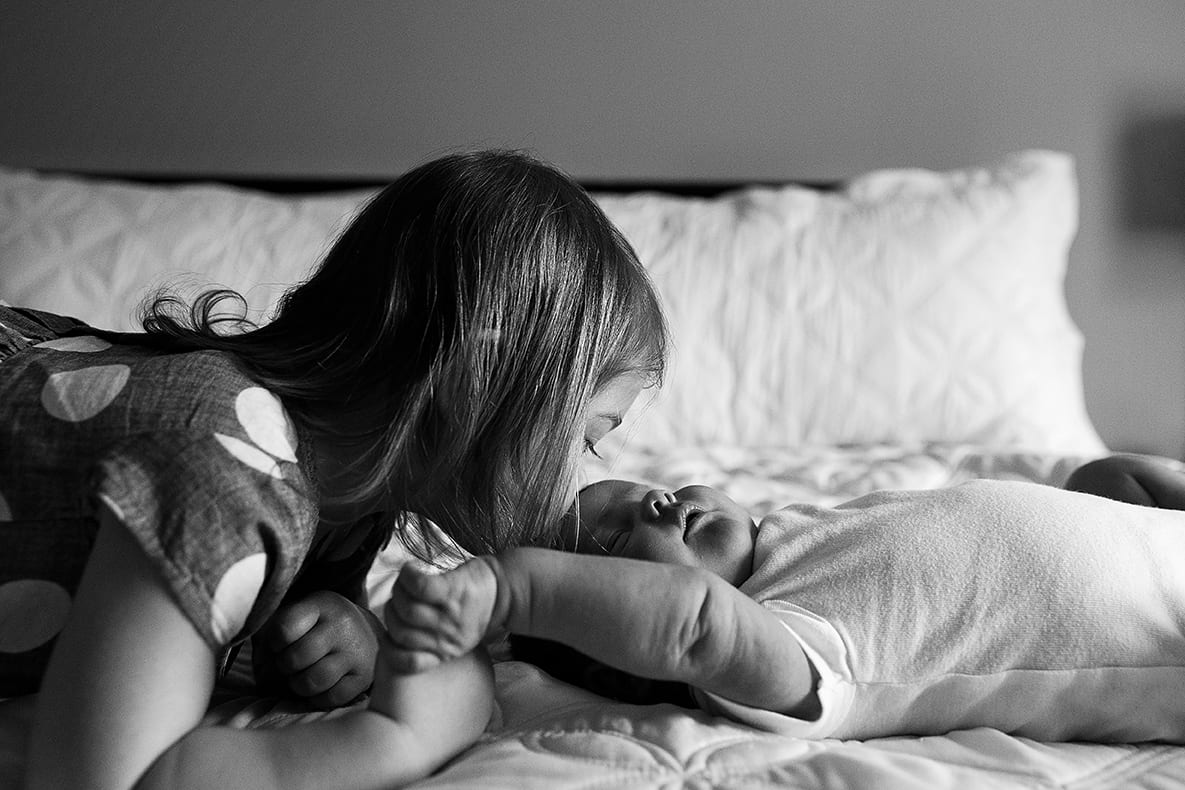 sister kissing baby brother during family portrait session