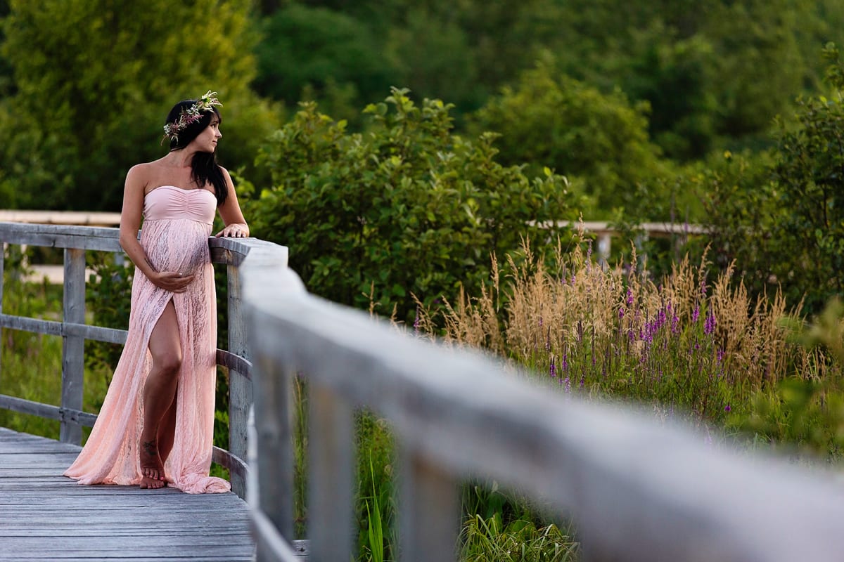 Expectant mom in blush dress on wooden boardwalk