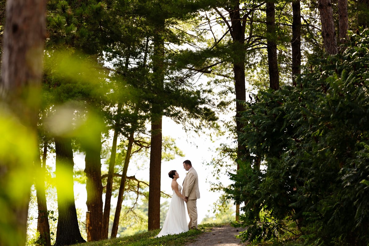 Bride and groom on path in sunlit trees at intimate Calabogie wedding