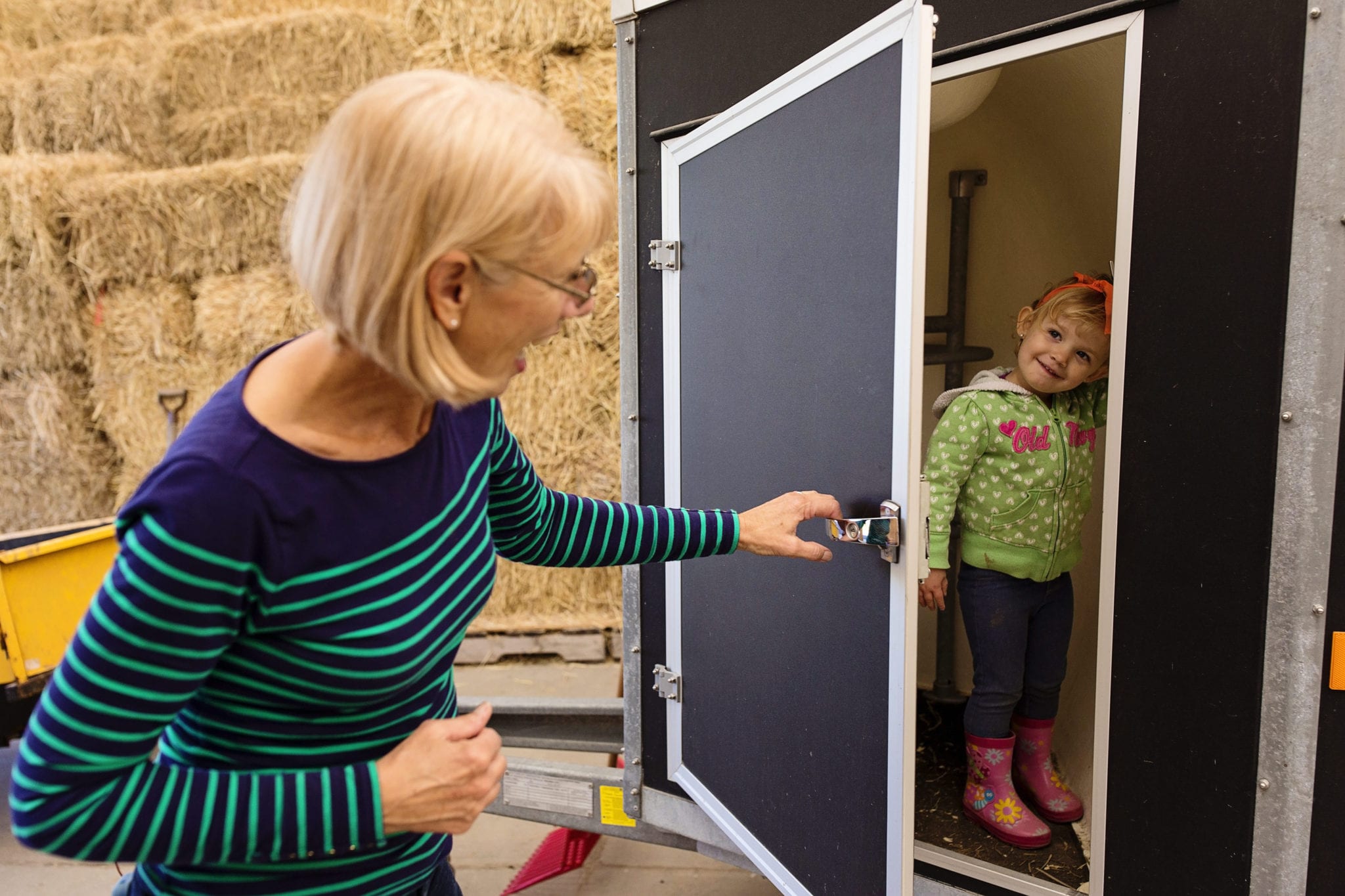 woman playing peekaboo with grandaughter wearing headband and rubber boots