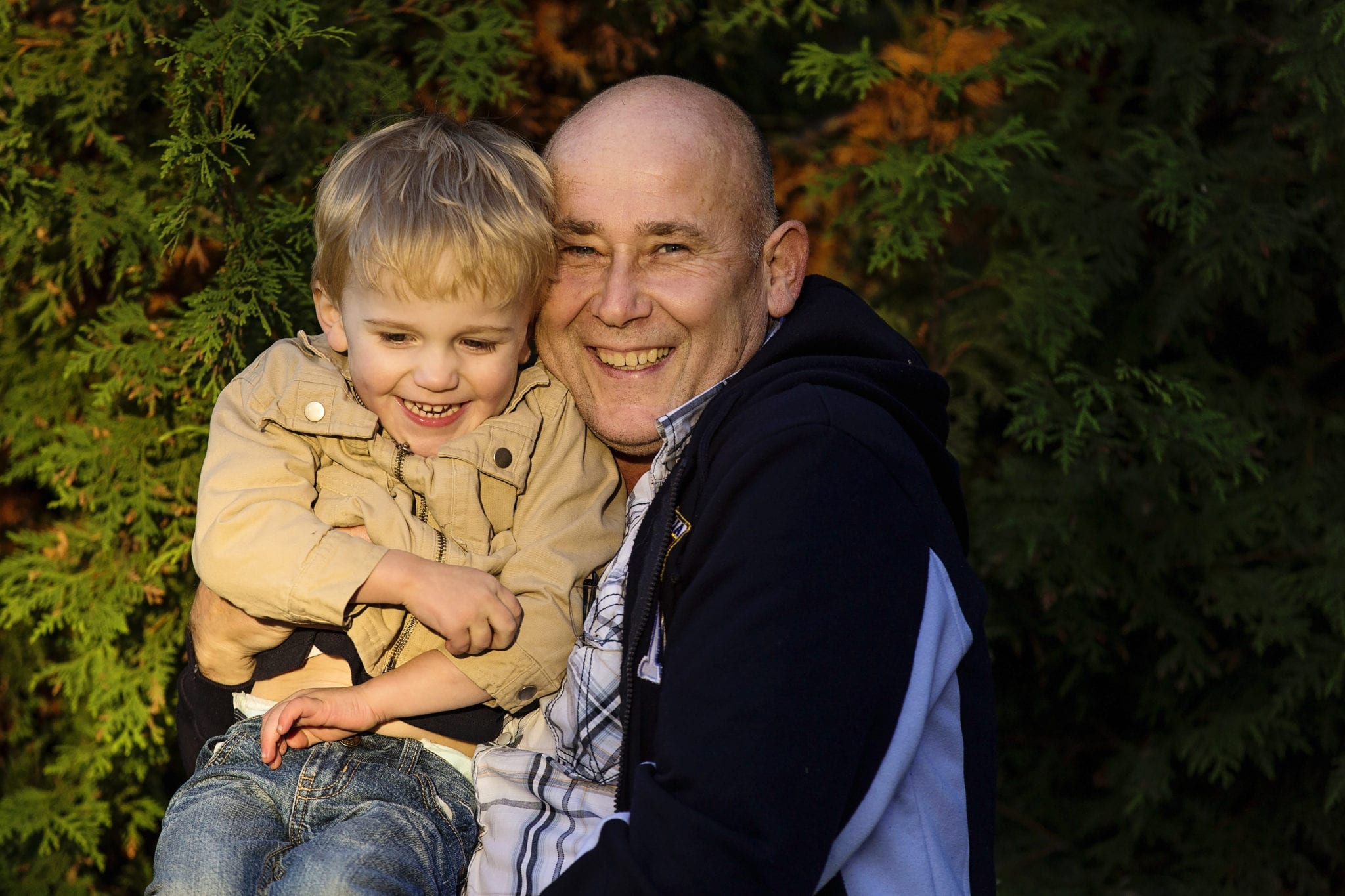 little boy in beige jacket sitting on dad's lap in rural Cornwall family shoot