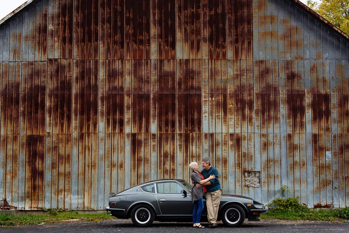 gritty tin wall background and couple with classic car in casual ontario portrait
