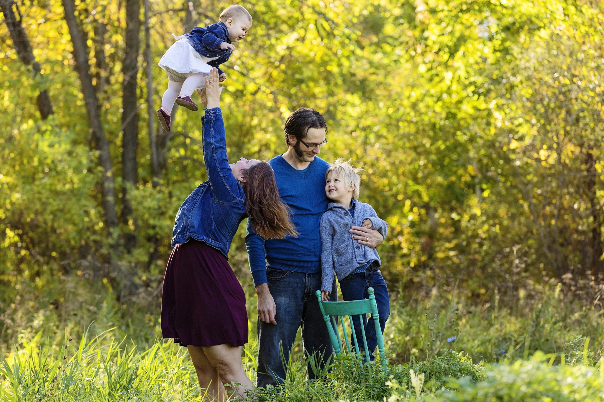 young and son and baby daughter with parents in sunny forest