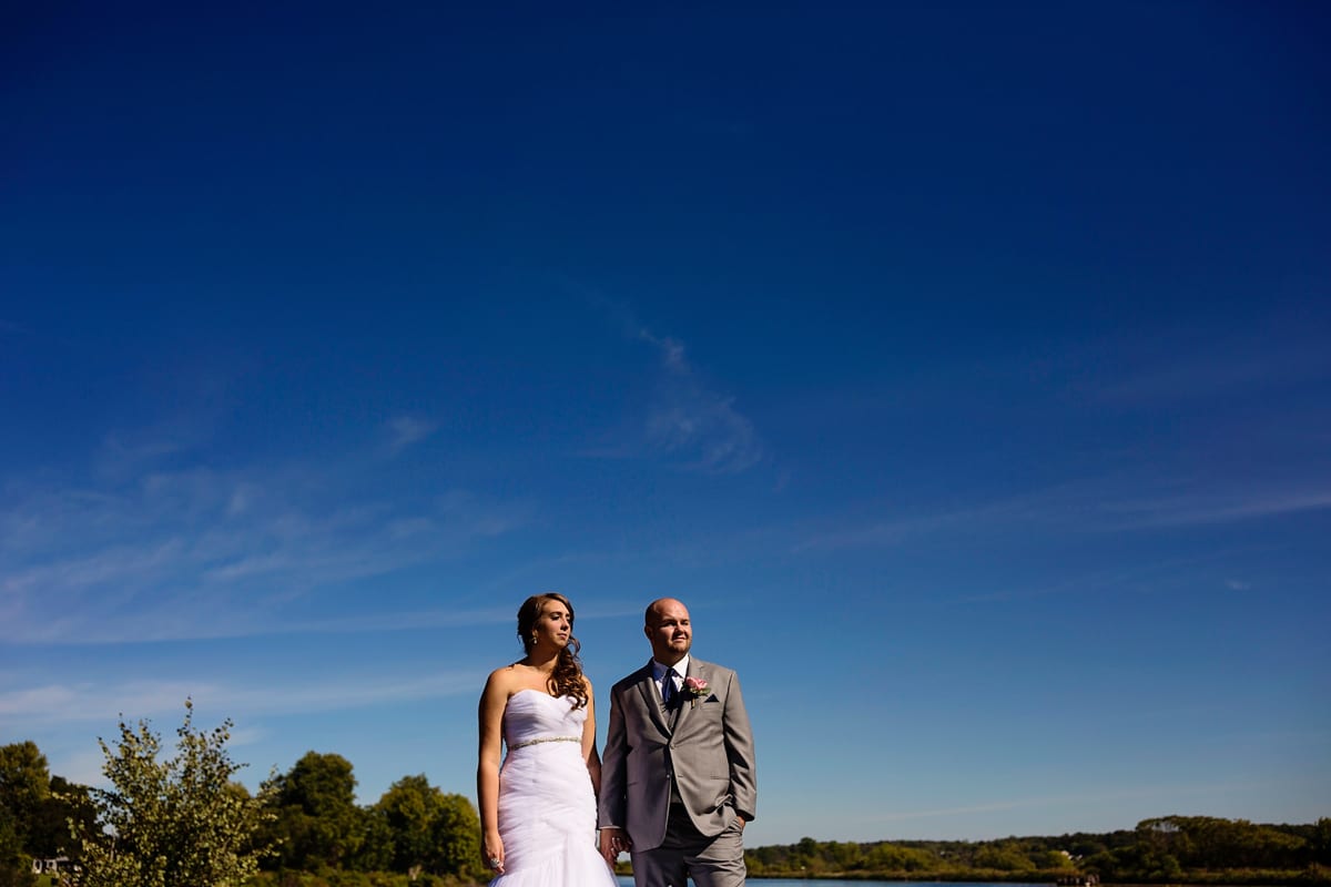 bride and groom look towards sun while holding hands