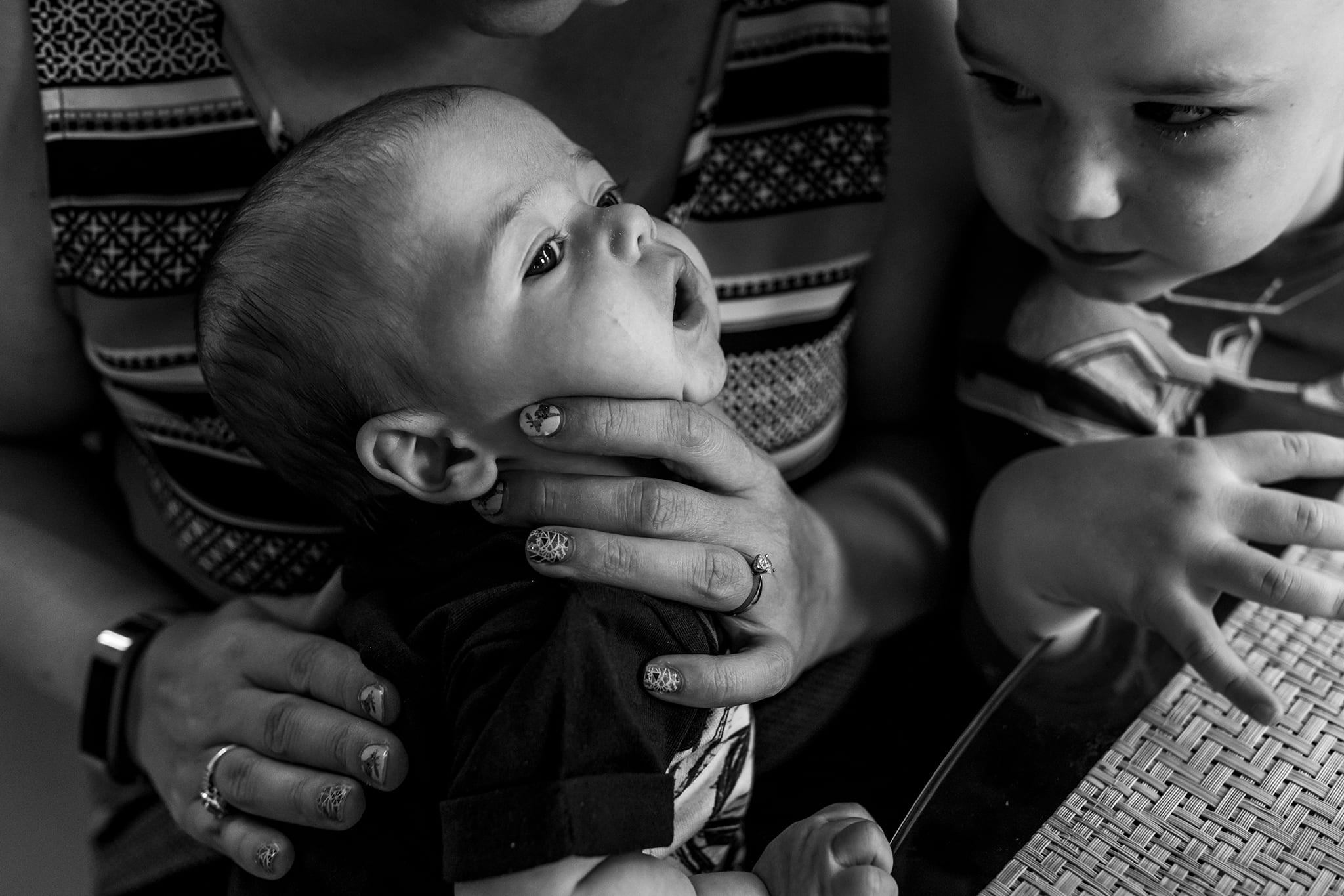 baby held by mom for burping while brother watches closely during Toronto family session