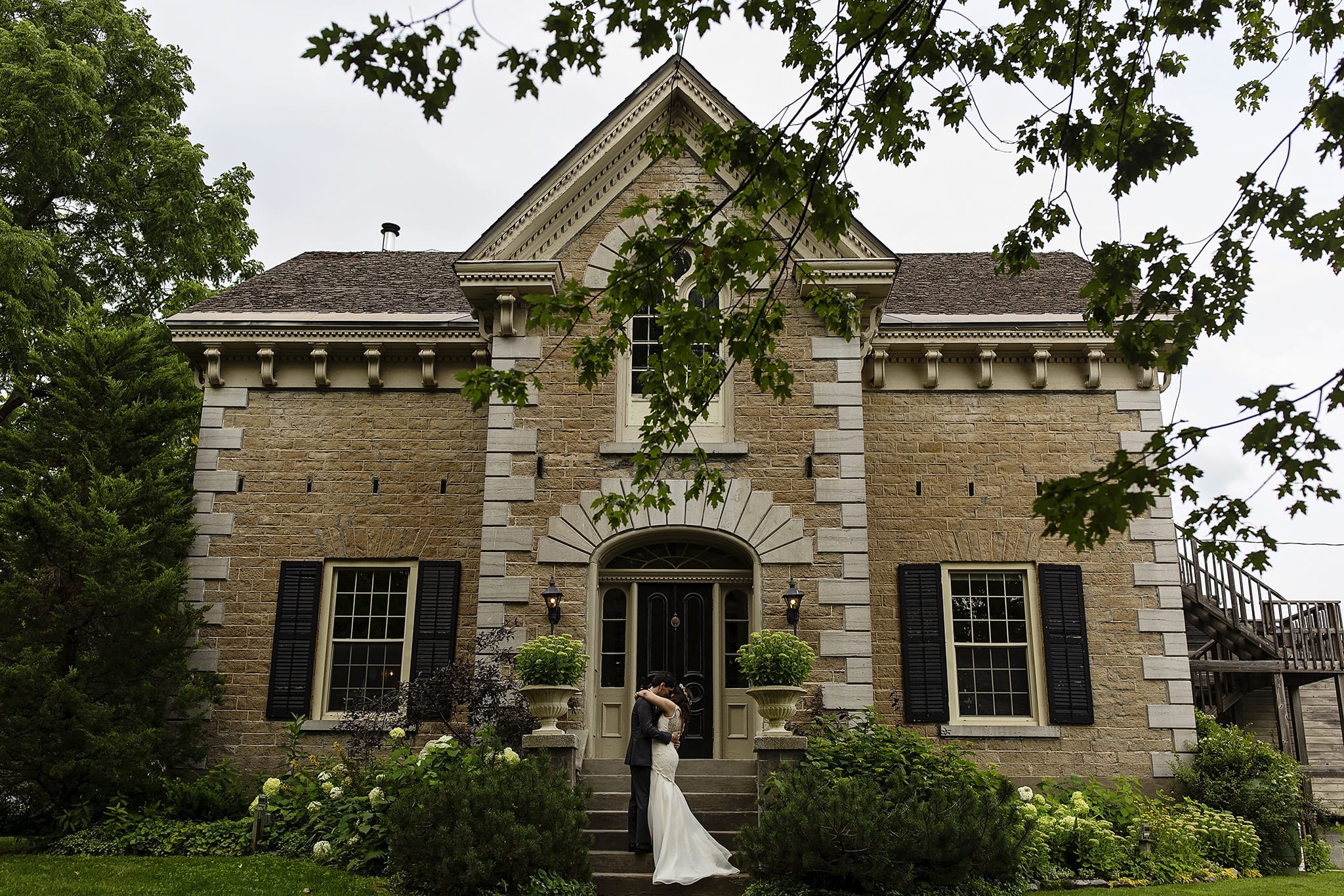 bride and groom embrace during first look on front steps of Strathmere Inn