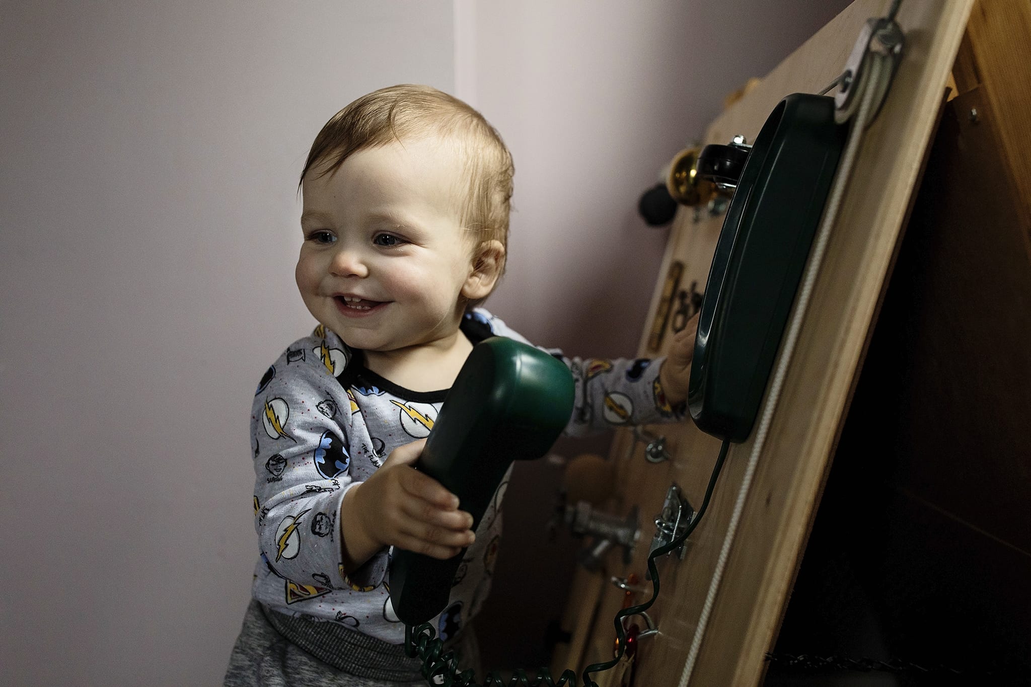 boy stands in front of play centre holding phone during Winchester first birthday session