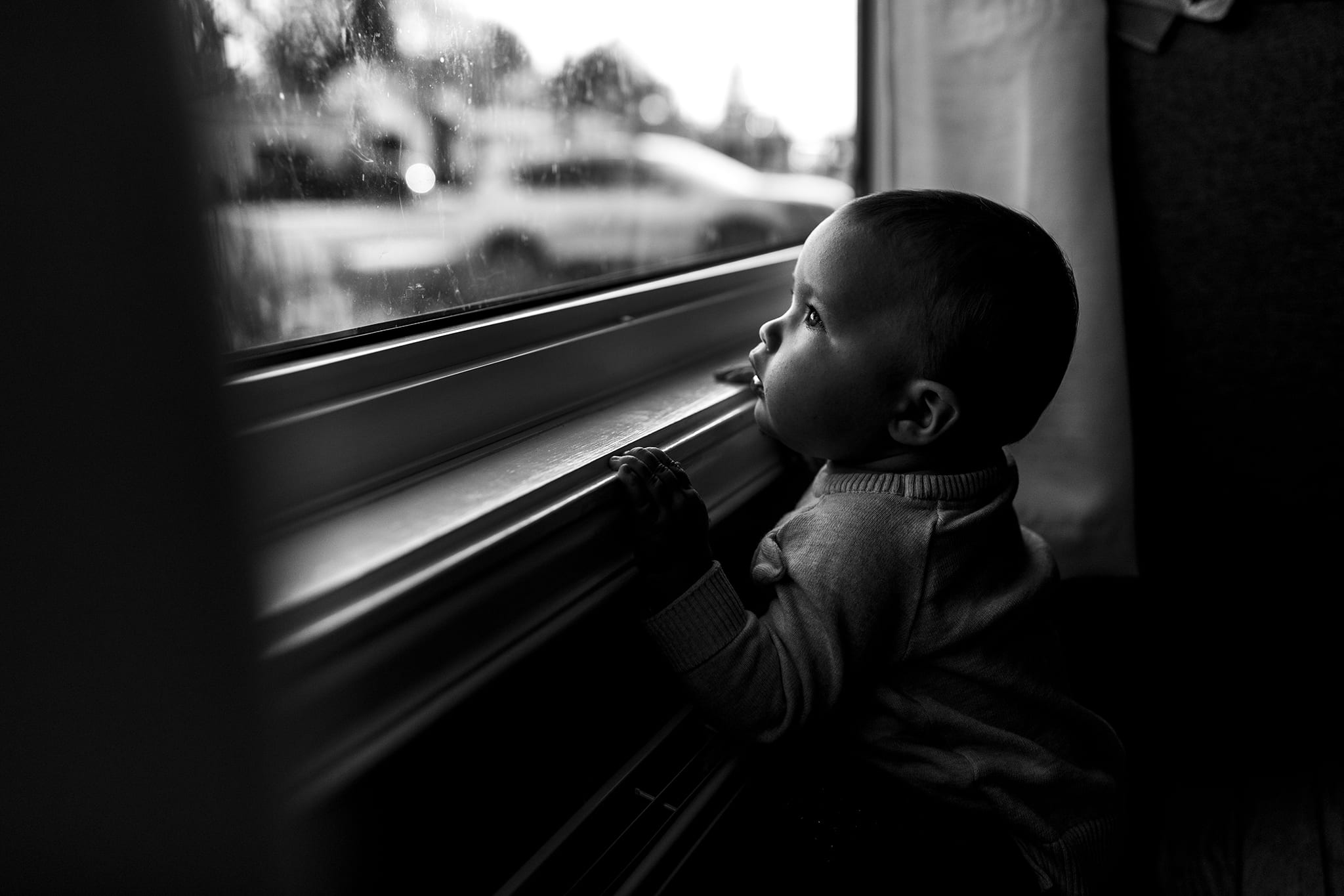 baby stands at window and looks outside