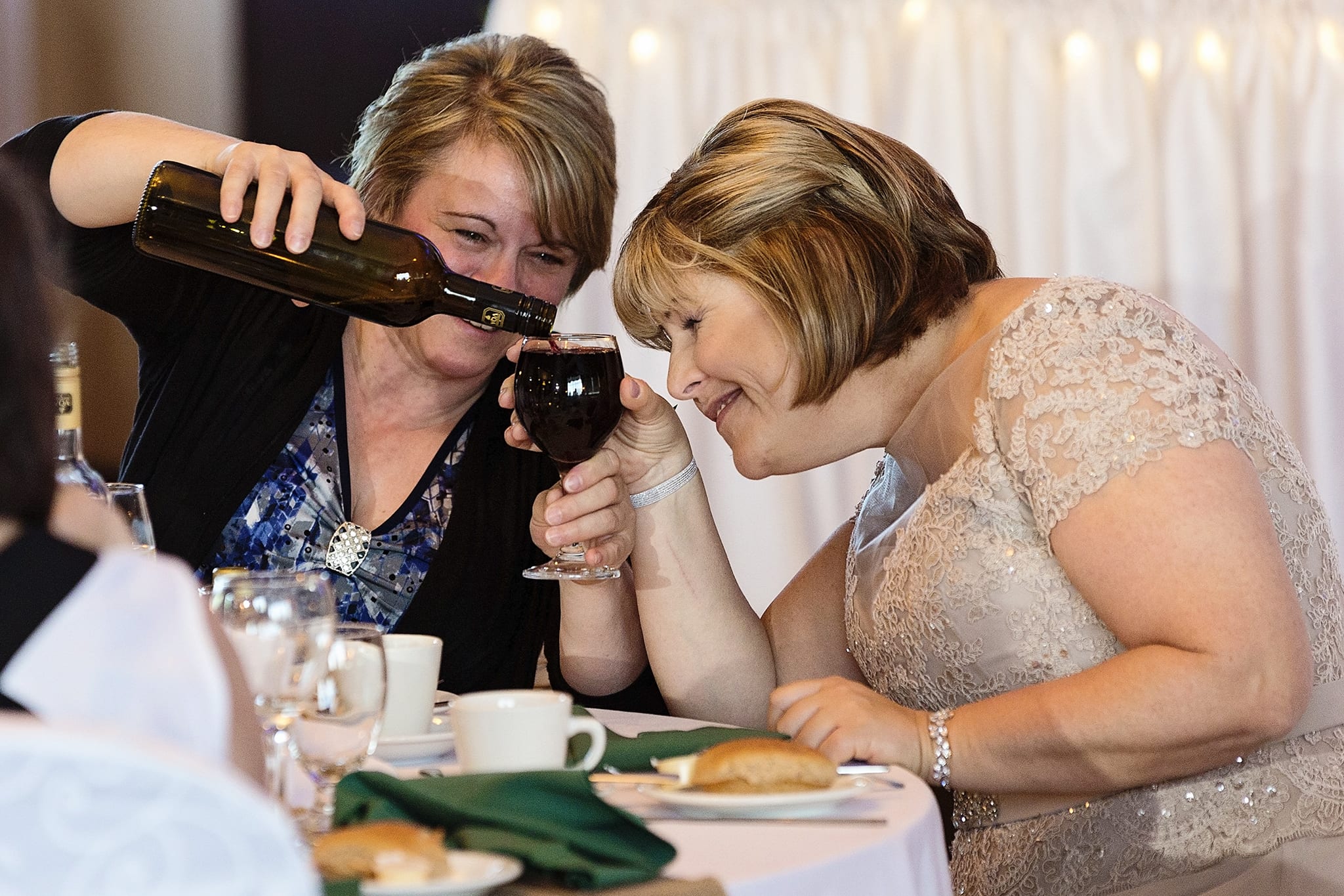 Woman fills wine glass to brim during Rockland wedding reception at River Rock Inn