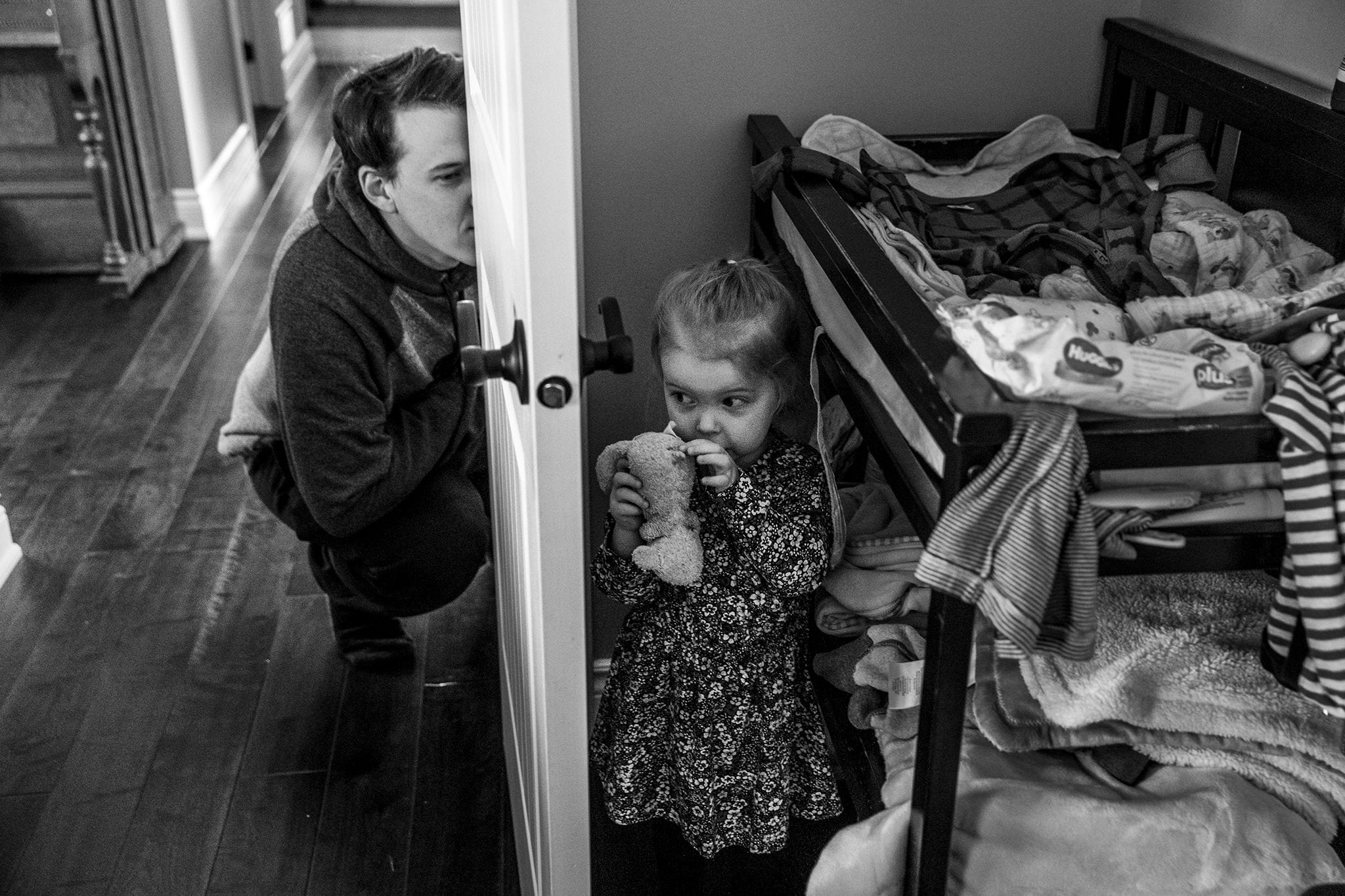 girl stands still while dad peeks through door at her