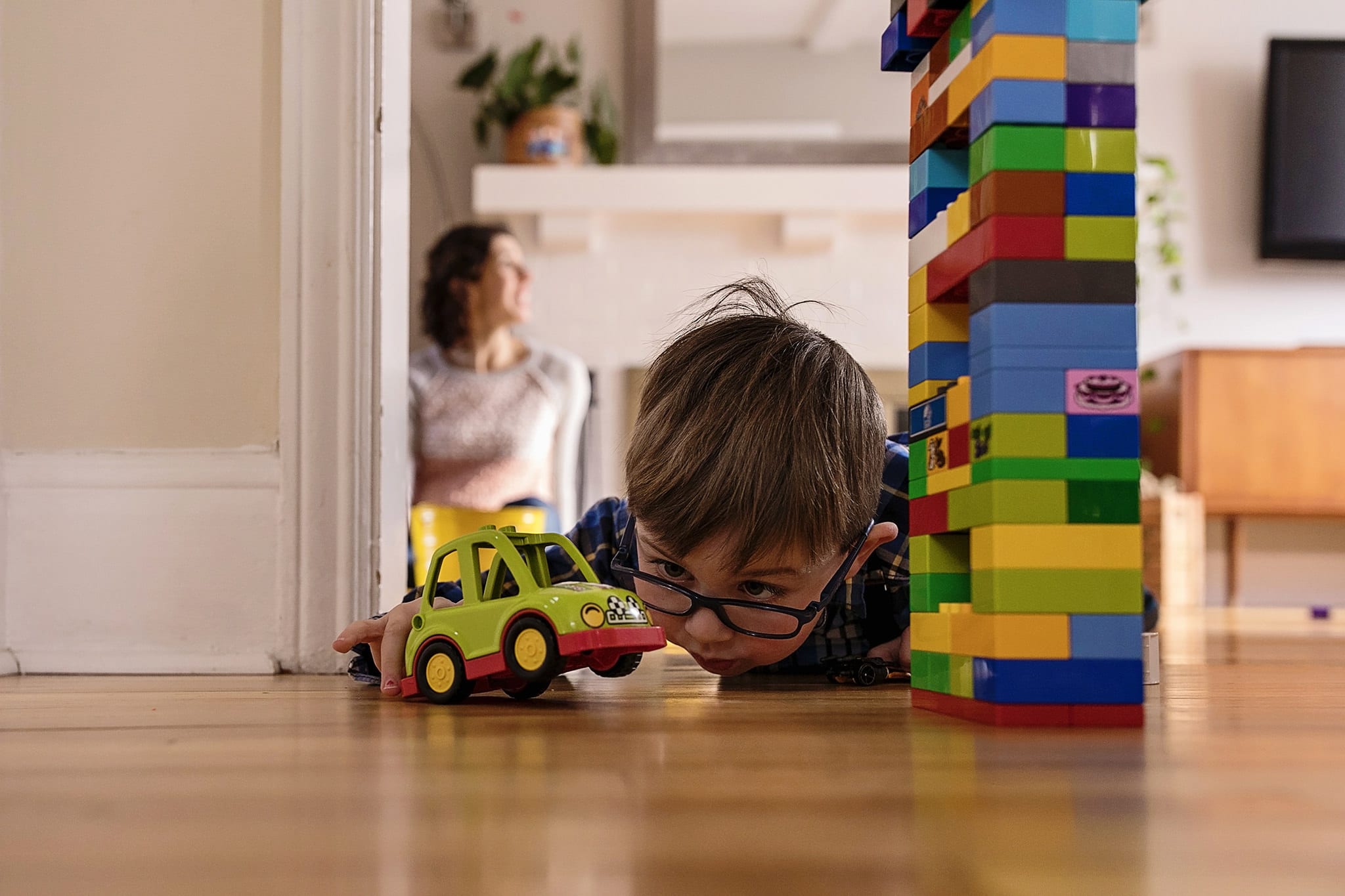 Boy lying on floor while playing with building blocks and car during Cornwall Winter Family Session