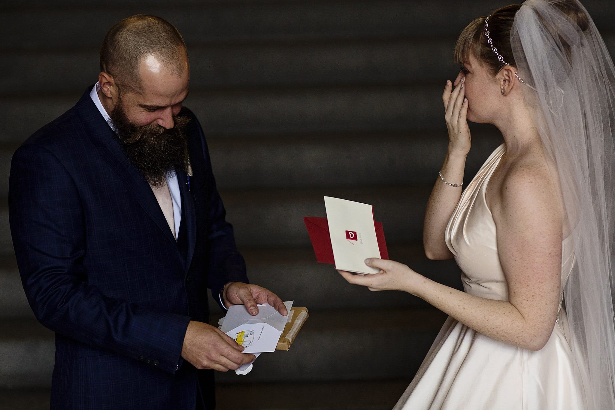 bride and groom each hold card and bride wipes tears
