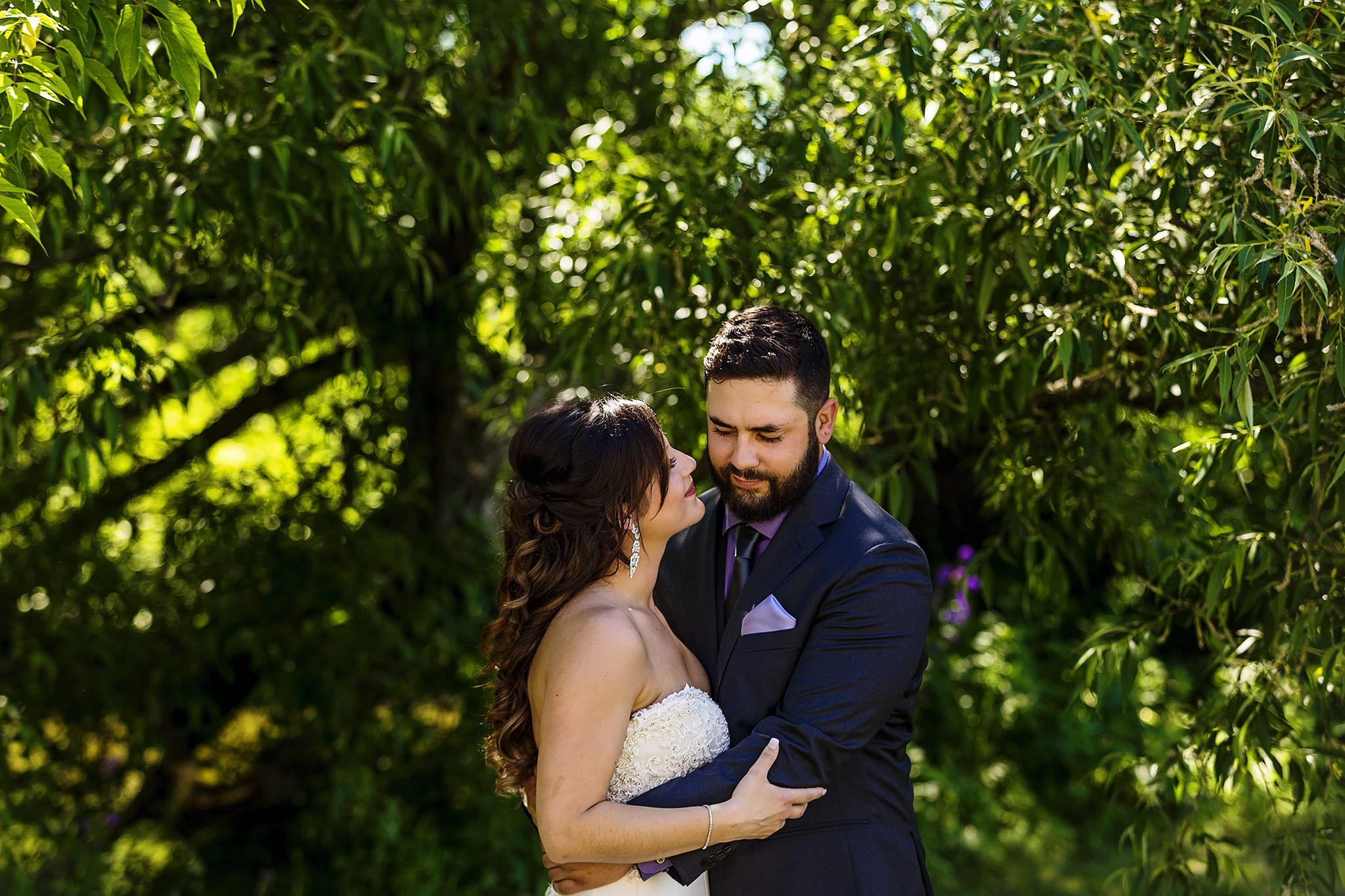 groom with purple pocket square wraps arms around bride while she looks up at him