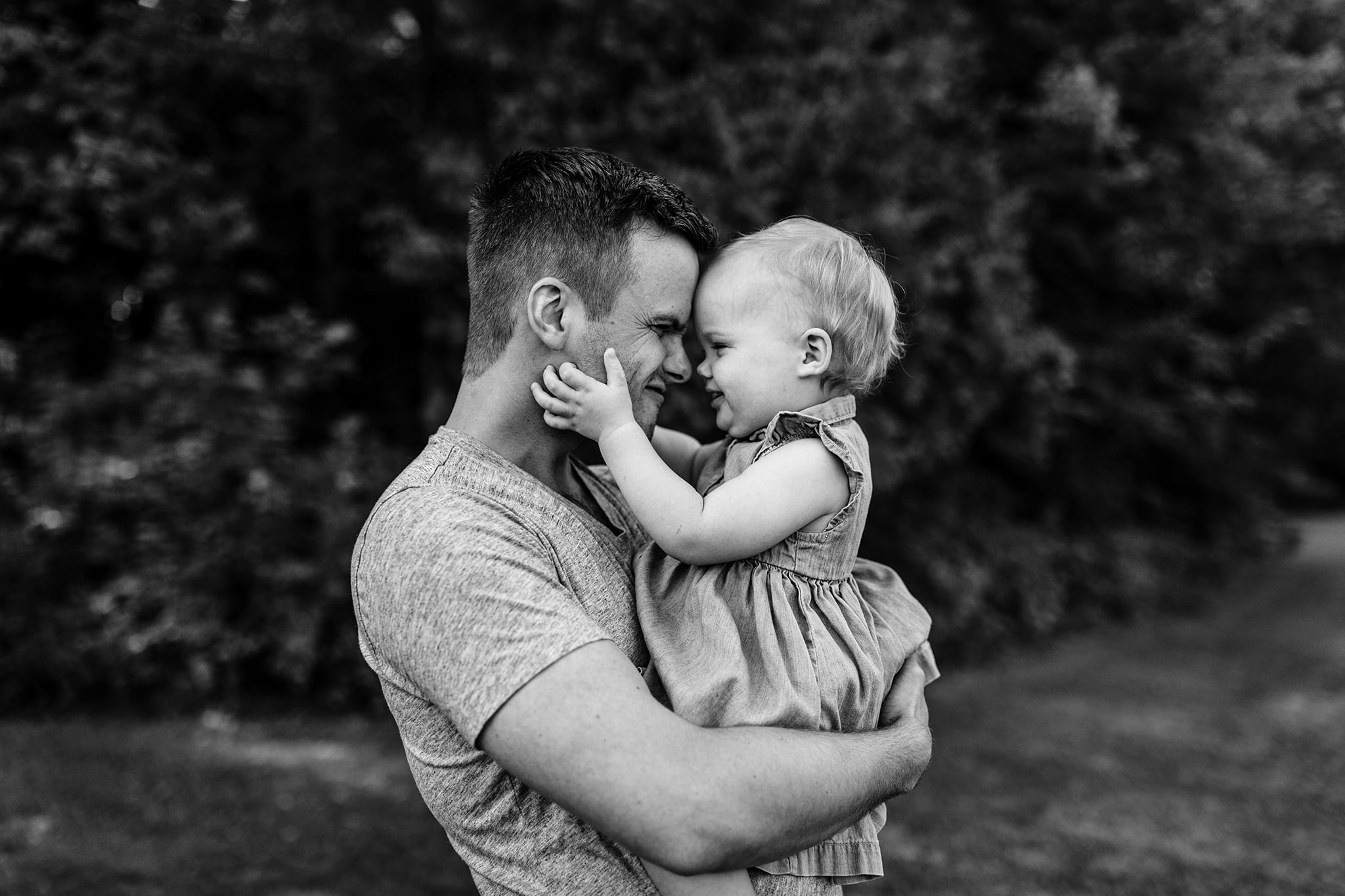 toddler grips dad's face and presses nose against his during casual family portraits