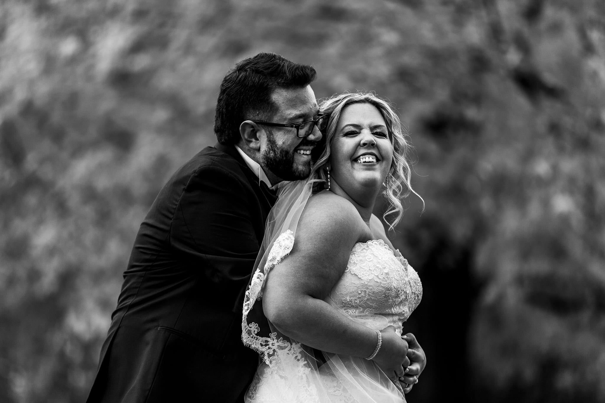 groom wraps arms around bride from behind while they laugh together