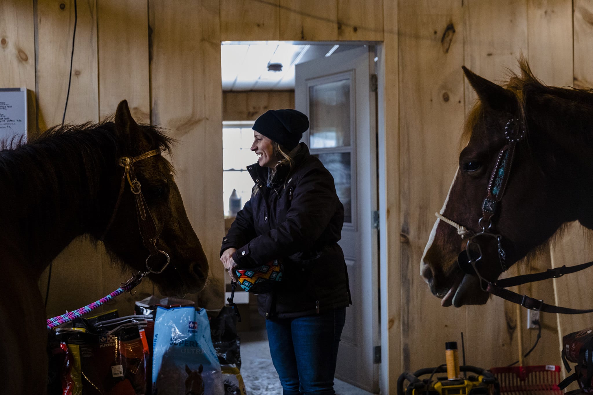 woman stands in doorway between two horses