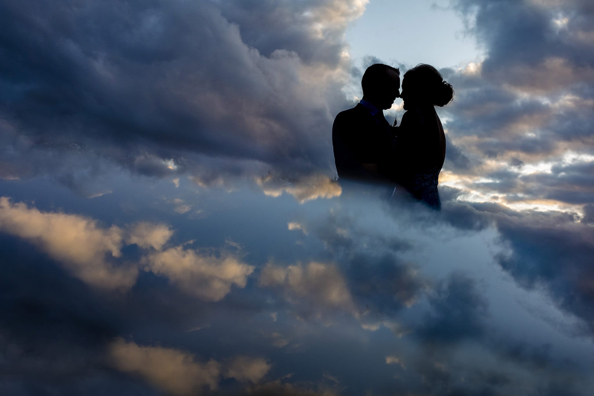 couple in silhouette against sky with dark blue tones