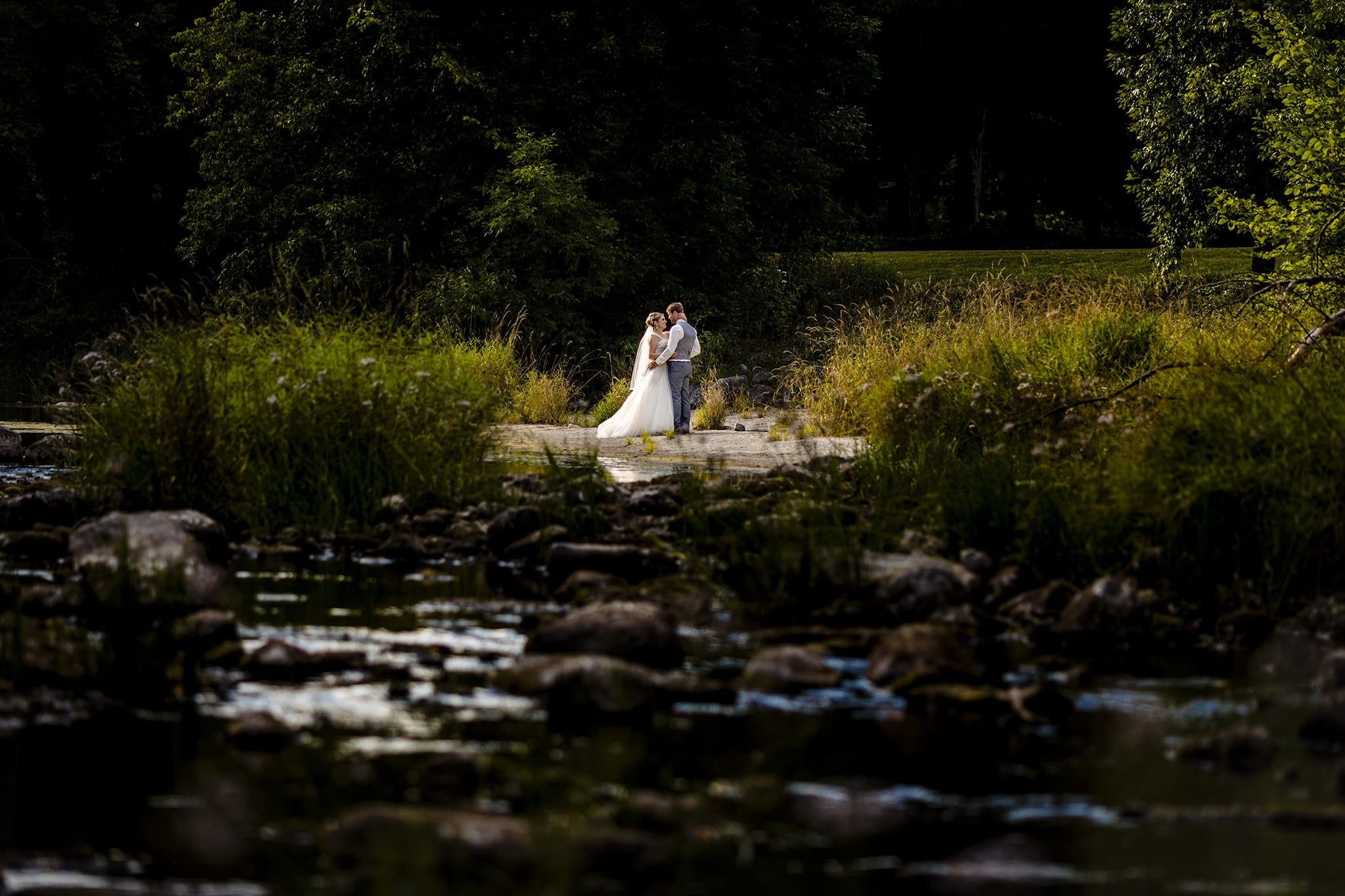 bride and groom stand close on riverbed in Williamstown