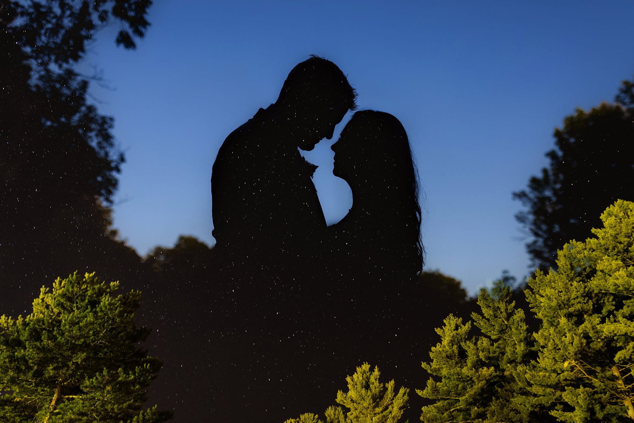 Couple in sikhouette against blue sky with stars layered