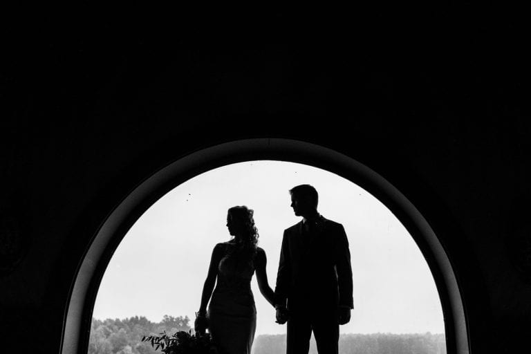 Bride and groom silhouetted in window of church for St Raphael's Ruins wedding