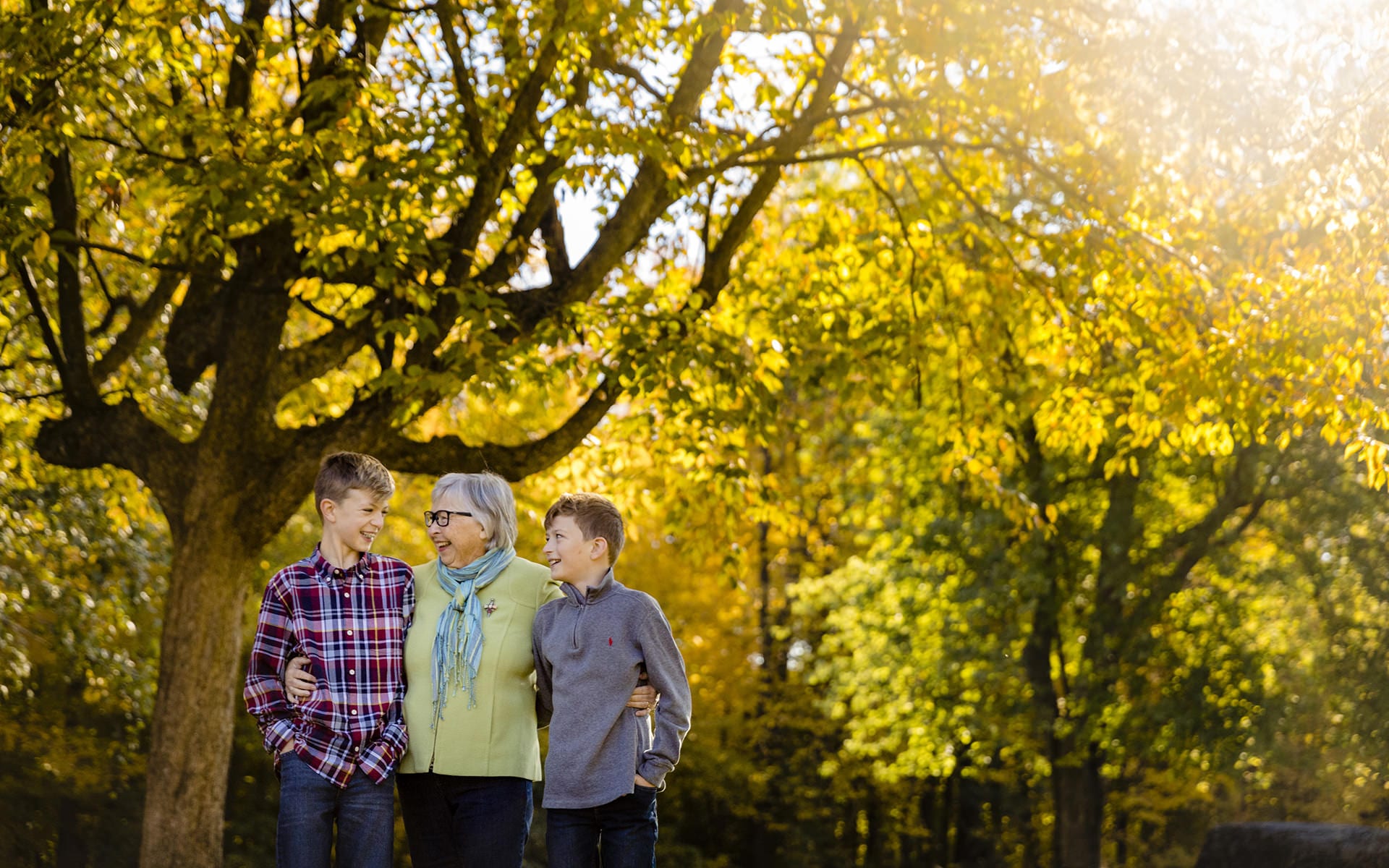 grandmother and two grandsons walking in autumn leaves