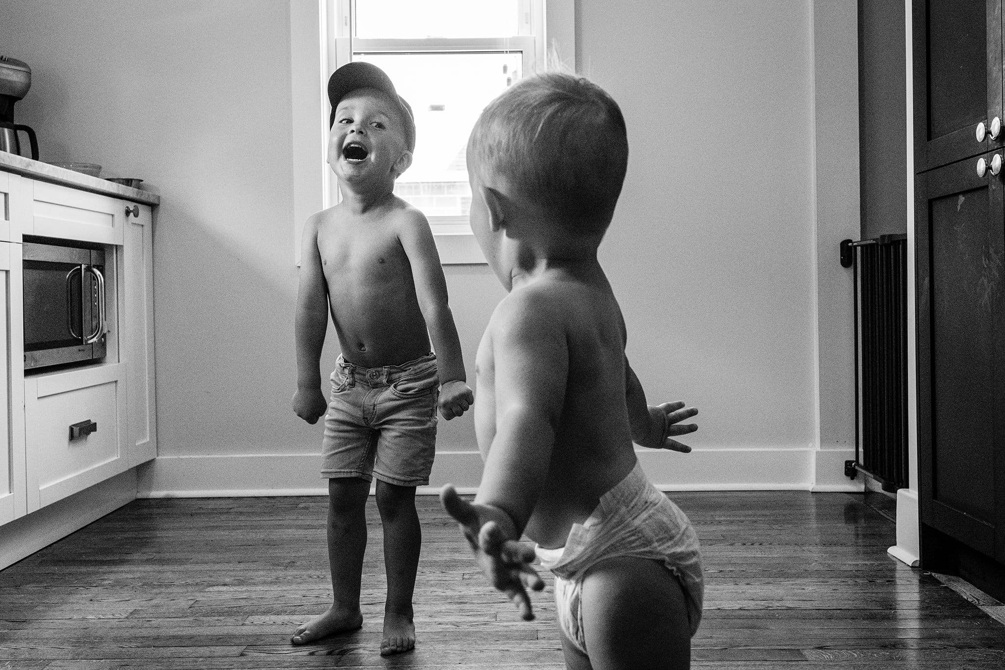shirtless boy yells happily while toddler brother stretches arms