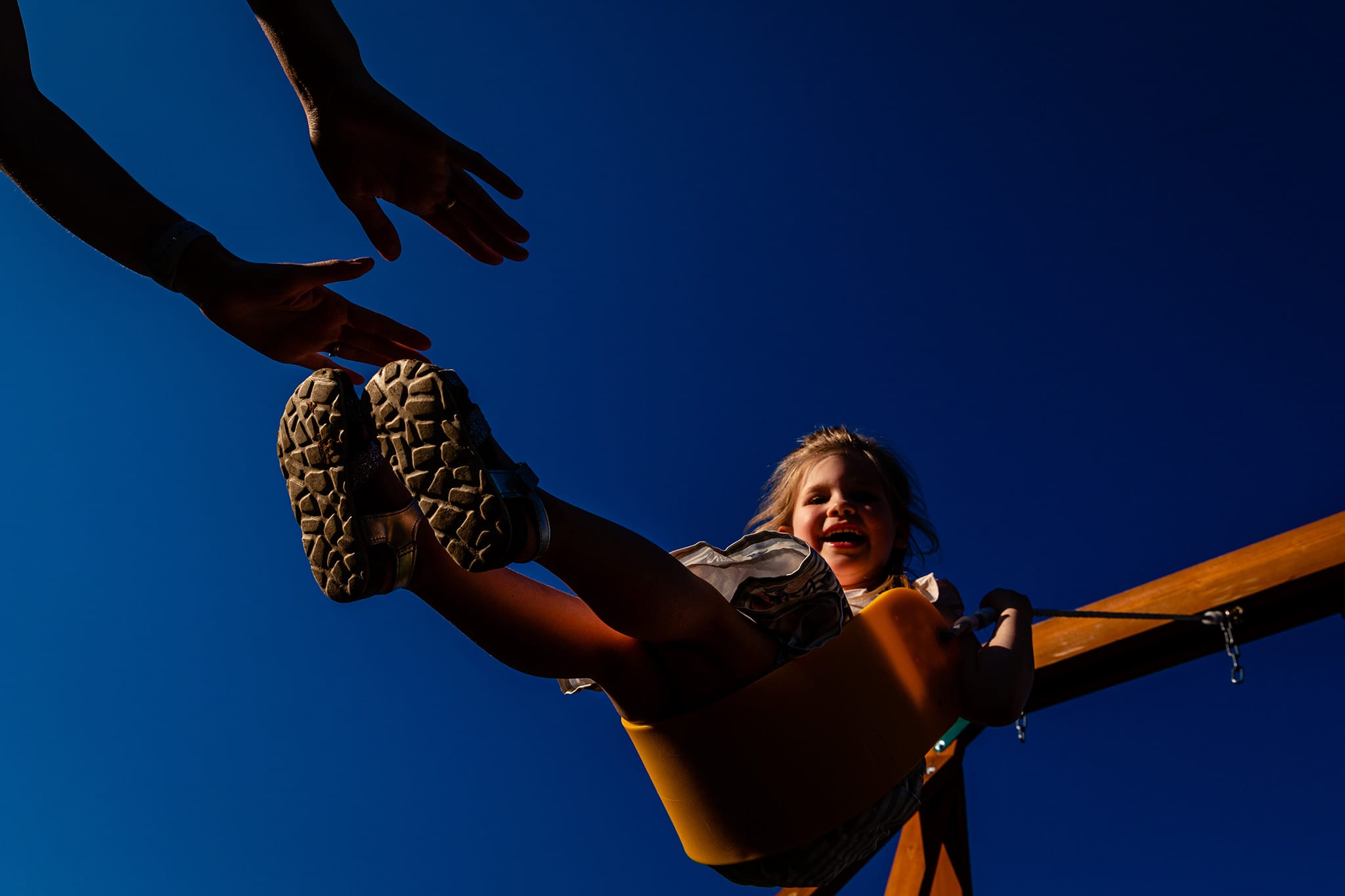 hands reach for little girl swinging high