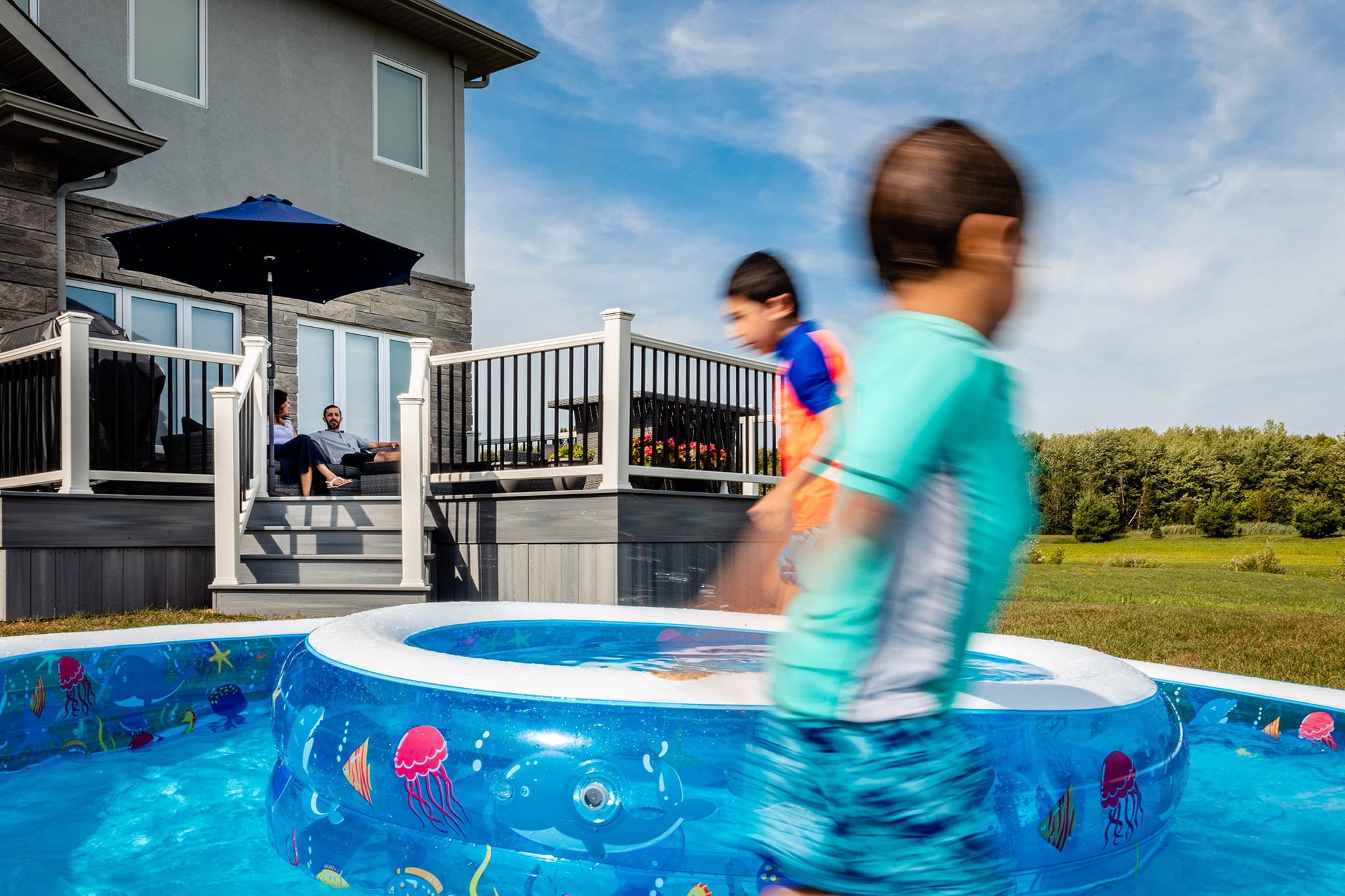 kids run in circular inflatable pool while parents sit on deck