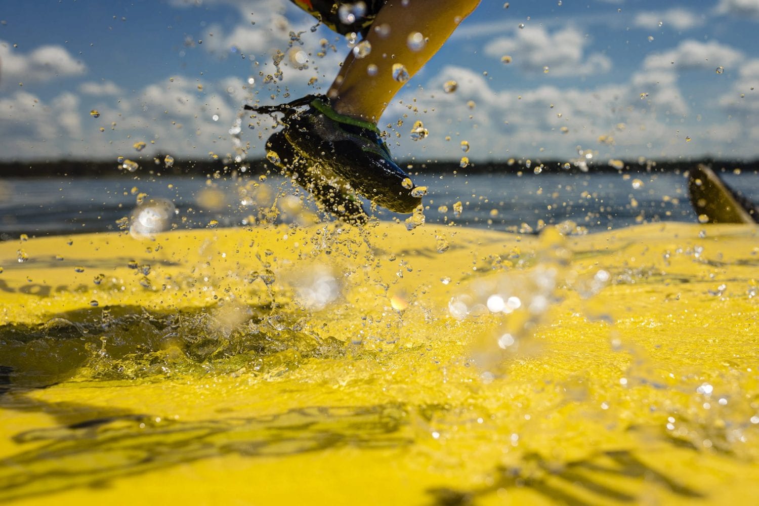 boy's feet jumping on yellow floating mat in St Lawrence River