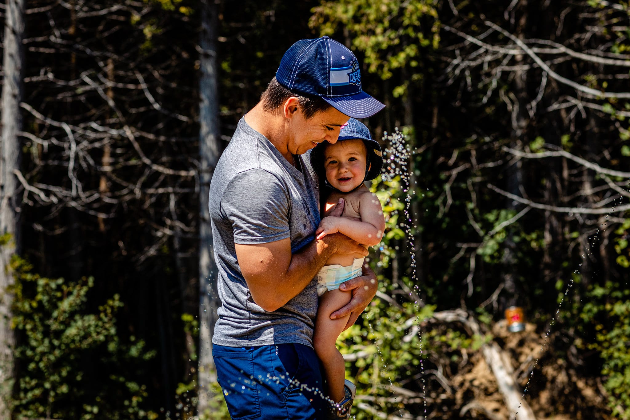 ingleside dad holds toddler near water spray from sprinkler