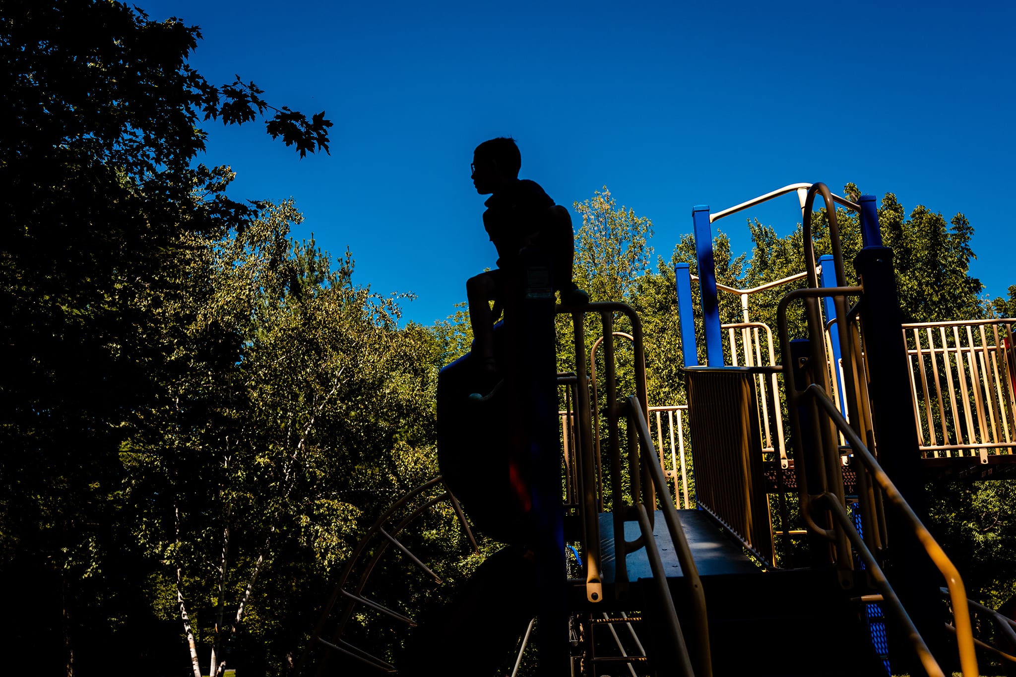 silhouette of boy on play structure