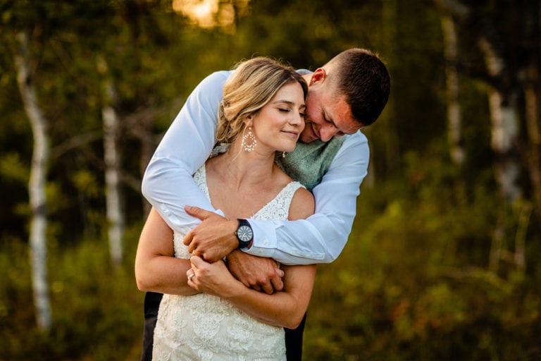 bride leans back against groom while wrapped in his arms