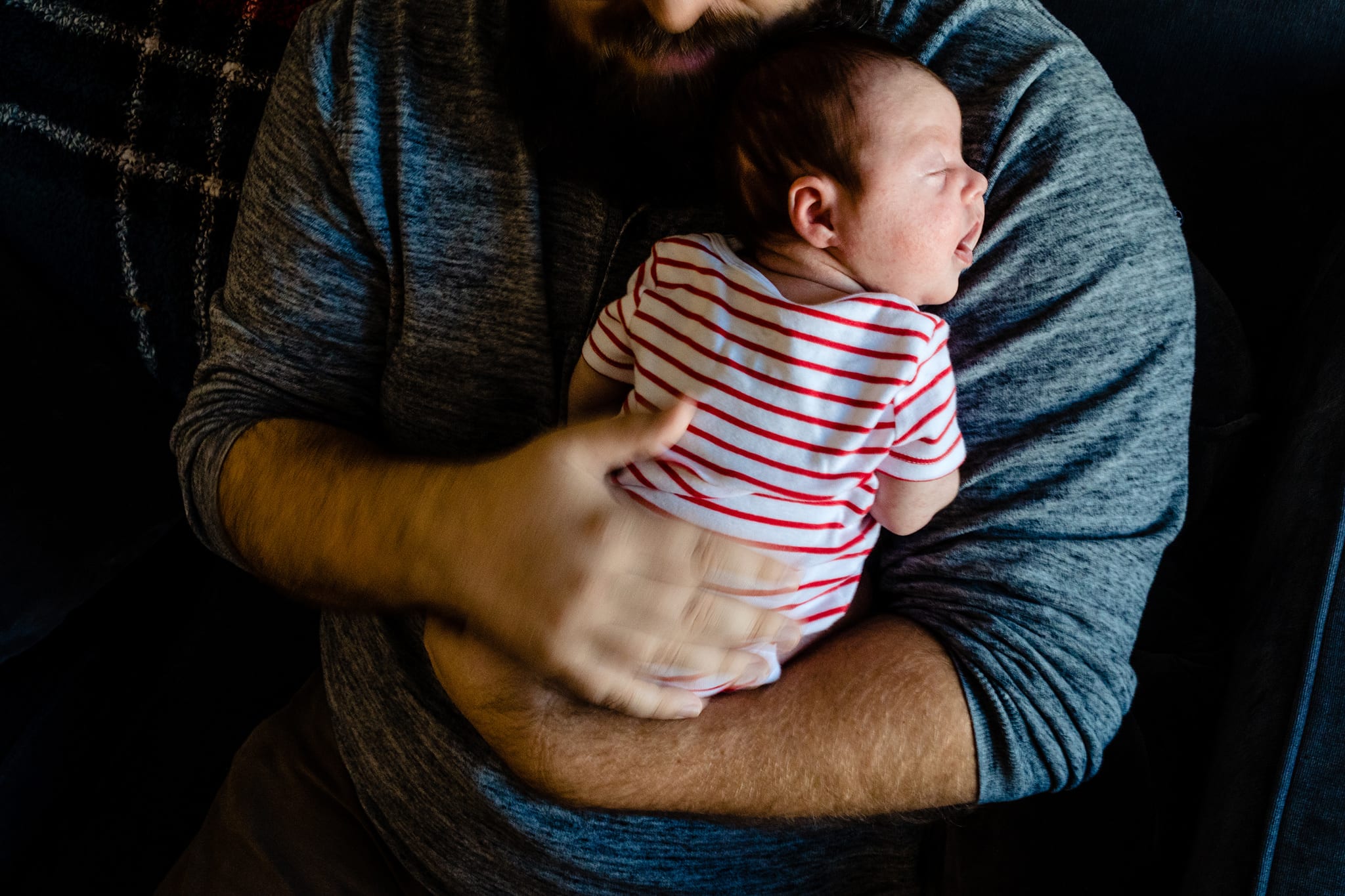 father sits on couch and rubs daughter's back during Downtown Cornwall Newborn Session