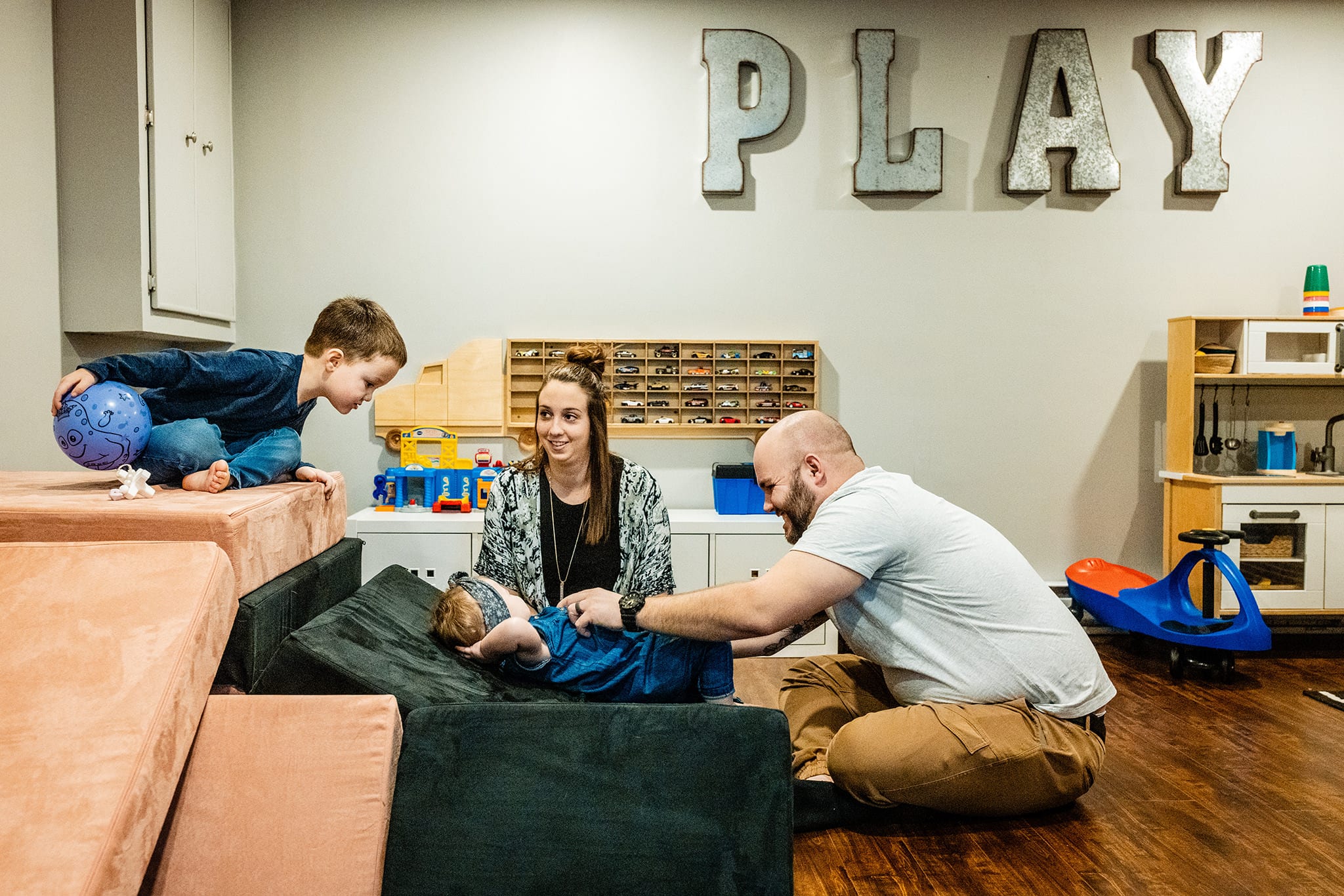 family on mats in playroom under sign reading 