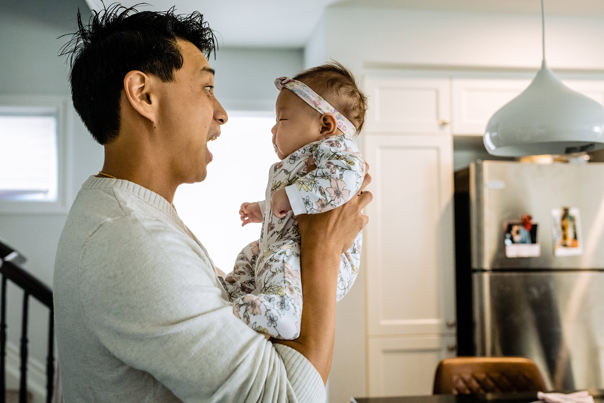 Father holds baby as he makes a surprised expression towards her.