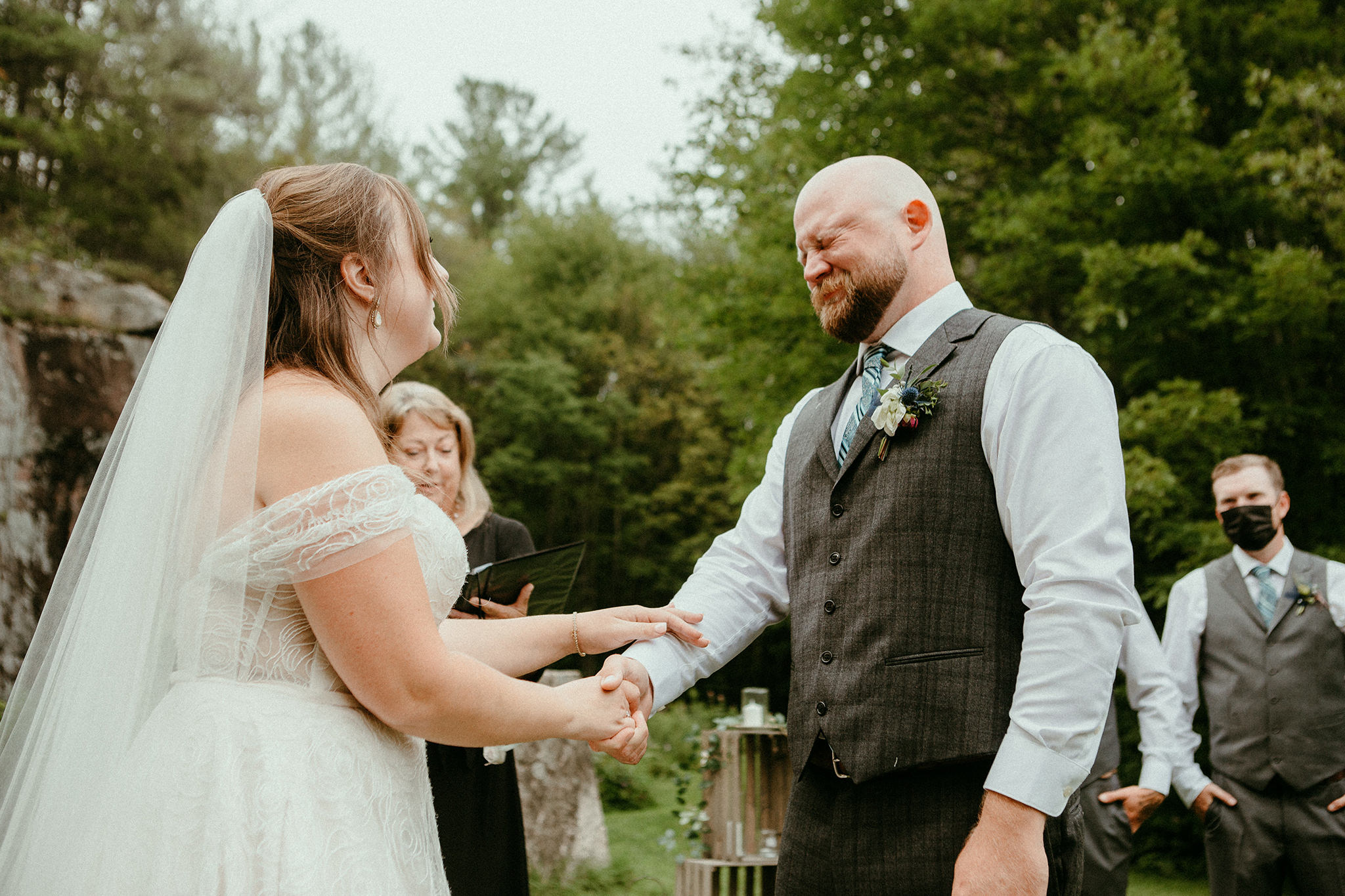 Bride holding Grooms hand while groom cries