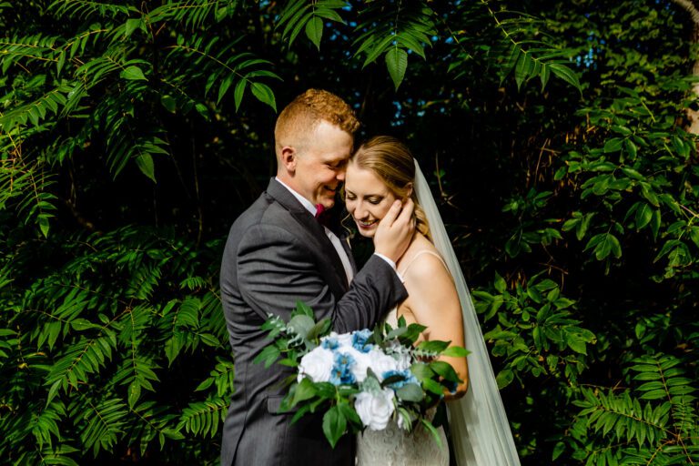 bride and groom stand close in front of sumac at the Marshes golf club